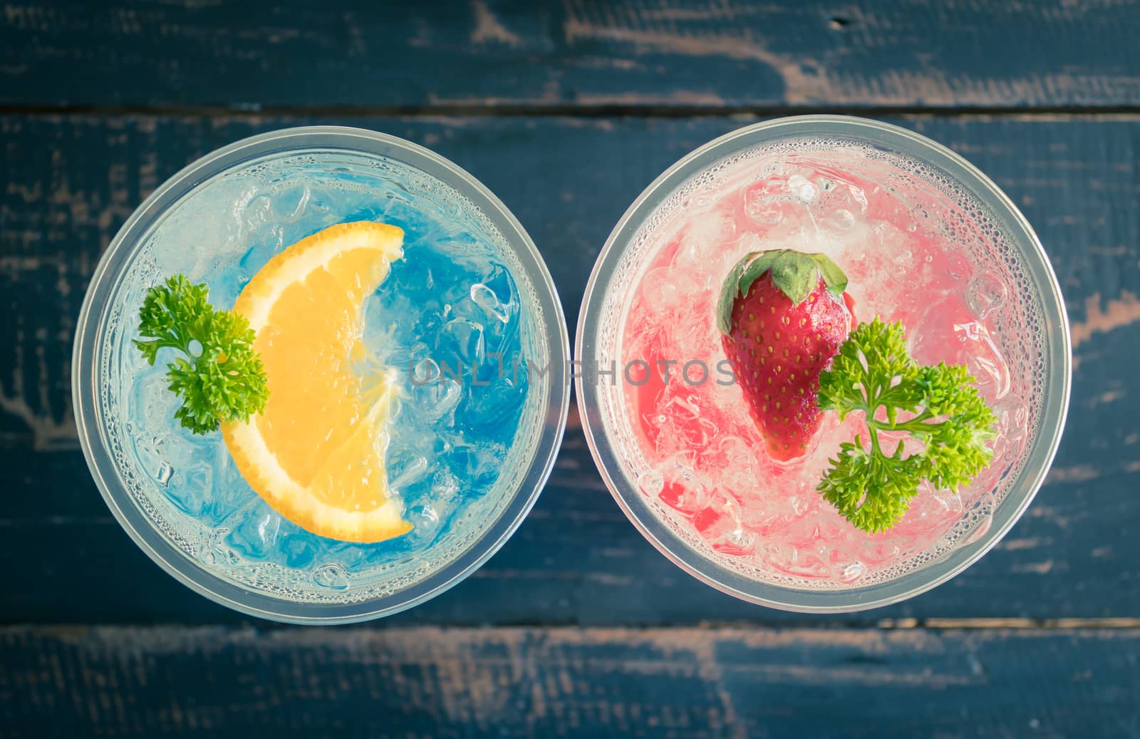 Blue Red Italian Soda Cold Beverage and Lemon Strawberry Fruit and Parsley. Blue Red Italian Soda Cold Beverage on wood table for food and drink category