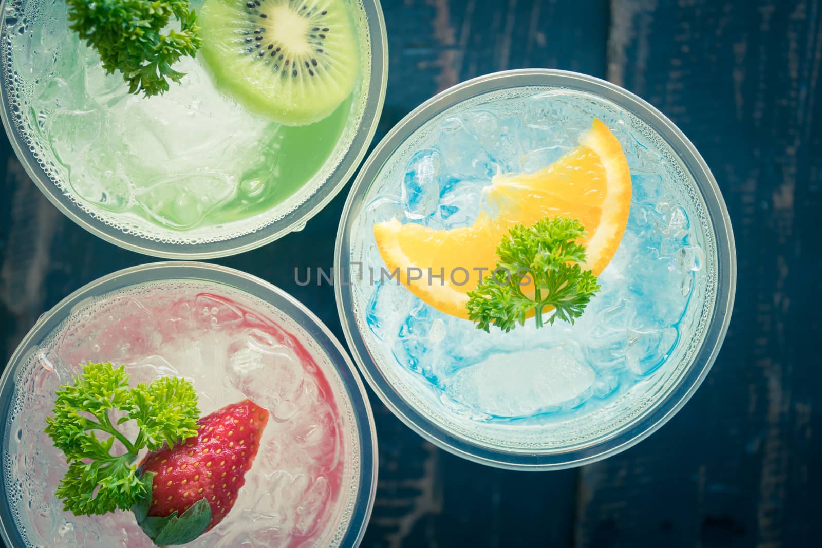 Blue Red Green Italian Soda Cold Beverage and Lemon Strawberry Kiwi Fruit and Parsley. Blue Red Green Italian Soda Cold Beverage on wood table for food and drink category