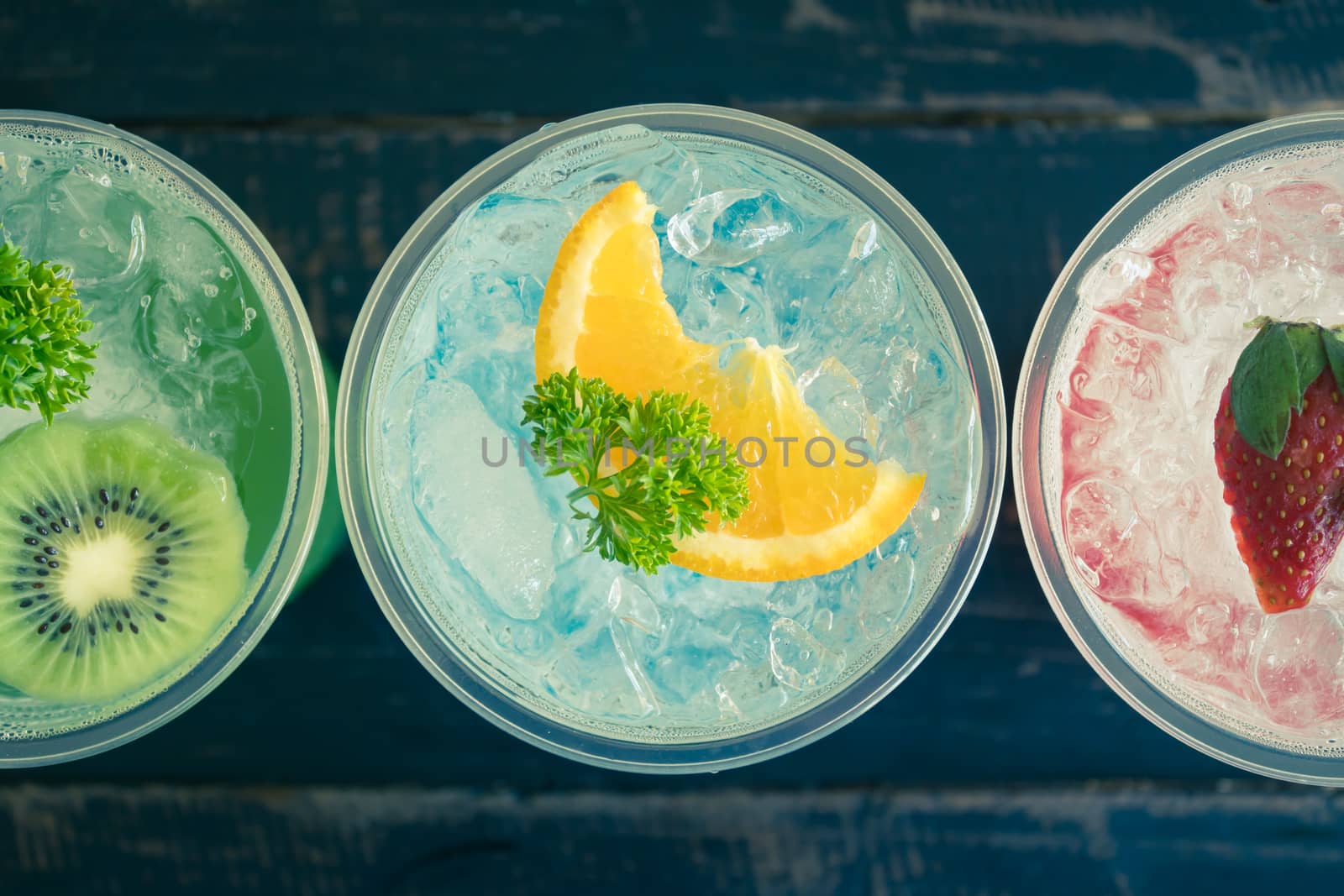 Green Blue Red Italian Soda Cold Beverage and Kiwi Lemon Strawberry Fruit and Parsley. Green Blue Red Italian Soda Cold Beverage on wood table for food and drink category