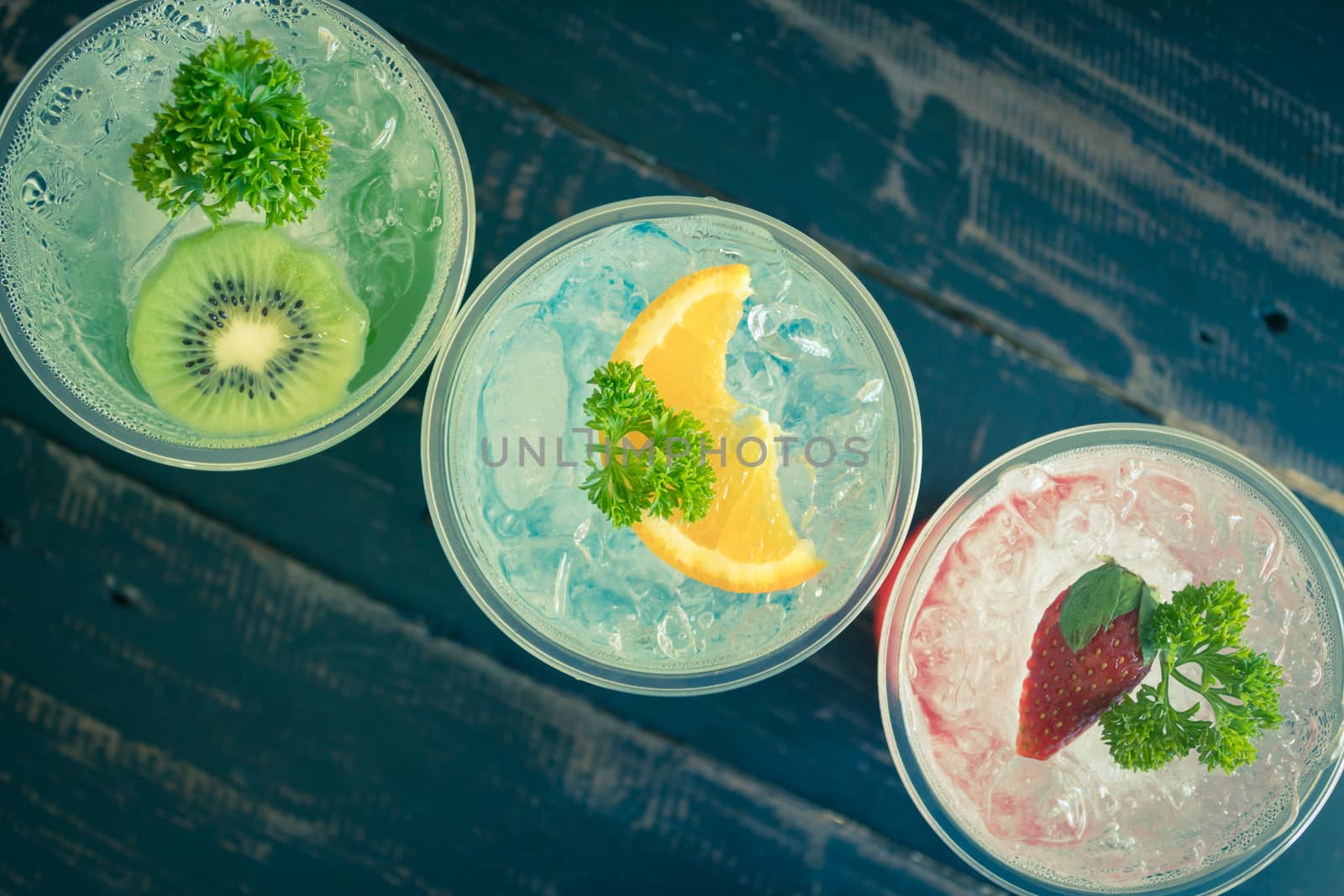 Green Blue Red Italian Soda Cold Beverage and Kiwi Lemon Strawberry Fruit and Parsley. Green Blue Red Italian Soda Cold Beverage on wood table for food and drink category