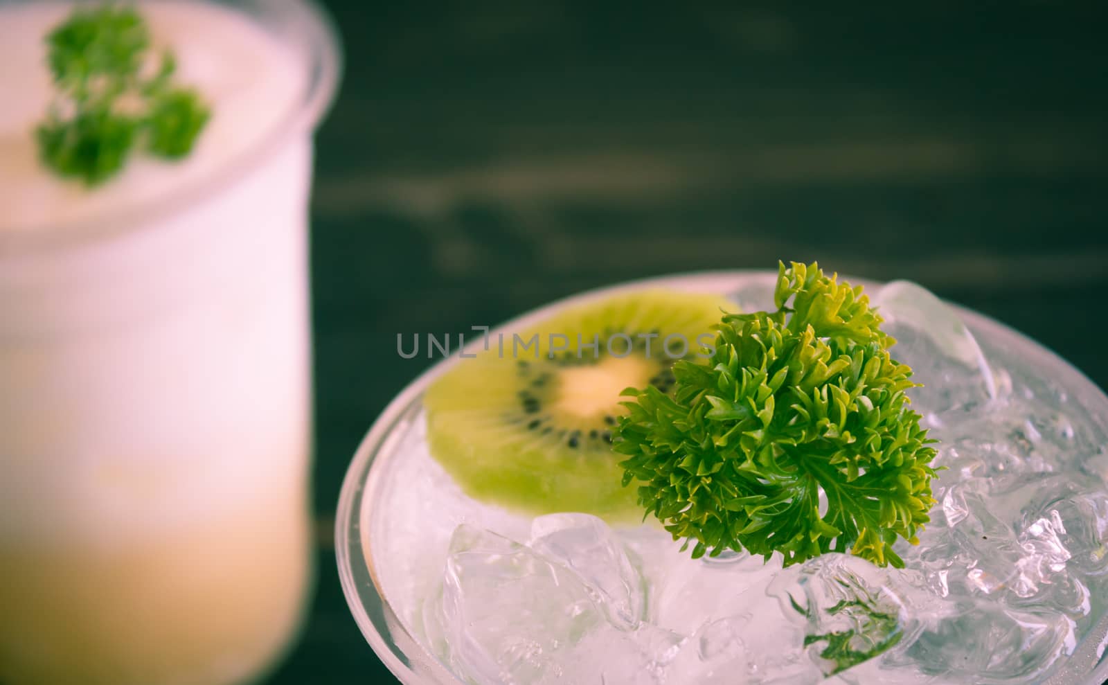 Green Italian Soda Cold Beverage and Kiwi Fruit and Parsley. Green Italian Soda Cold Beverage with Kiwi fruit and ice in glass on wood table. Green Italian Soda with Kiwi for food 
and drink category