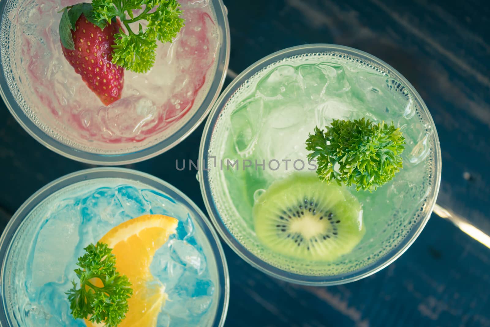 Green Red Blue Italian Soda Cold Beverage and Kiwi Strawberry Lemon Fruit and Parsley. Green Red Blue Italian Soda Cold Beverage on wood table for food and drink category