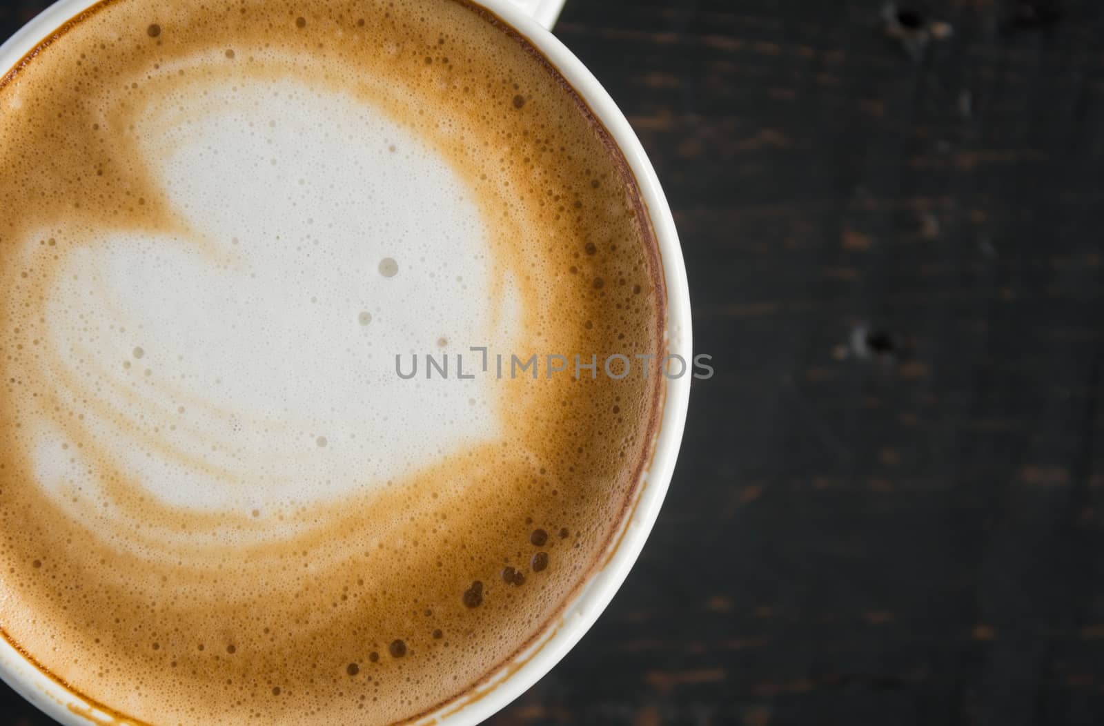 Flatlay Half Heart Shape Froth Milk Latte Art in White Coffee Cup on Black Wood Table. Heart shape froth milk Latte art hot beverage for coffee lover