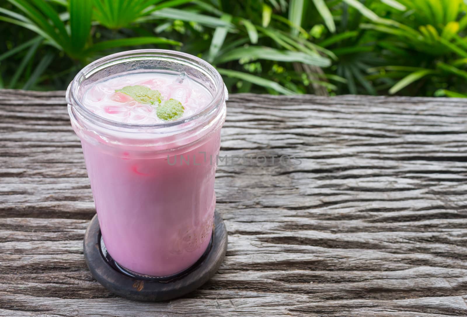 Pink Cold Milk Beverage or Cold Drinks and Peppermint Left Frame. Pink cold drinks and ice on wood table for drink