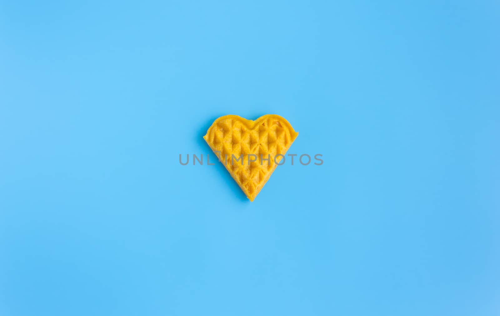 1 Piece Heart Shape Waffle on Blue Pastel Background Minimalist Style Wide Angle. Heart shape waffle dessert in minimalist style for food and dessert category