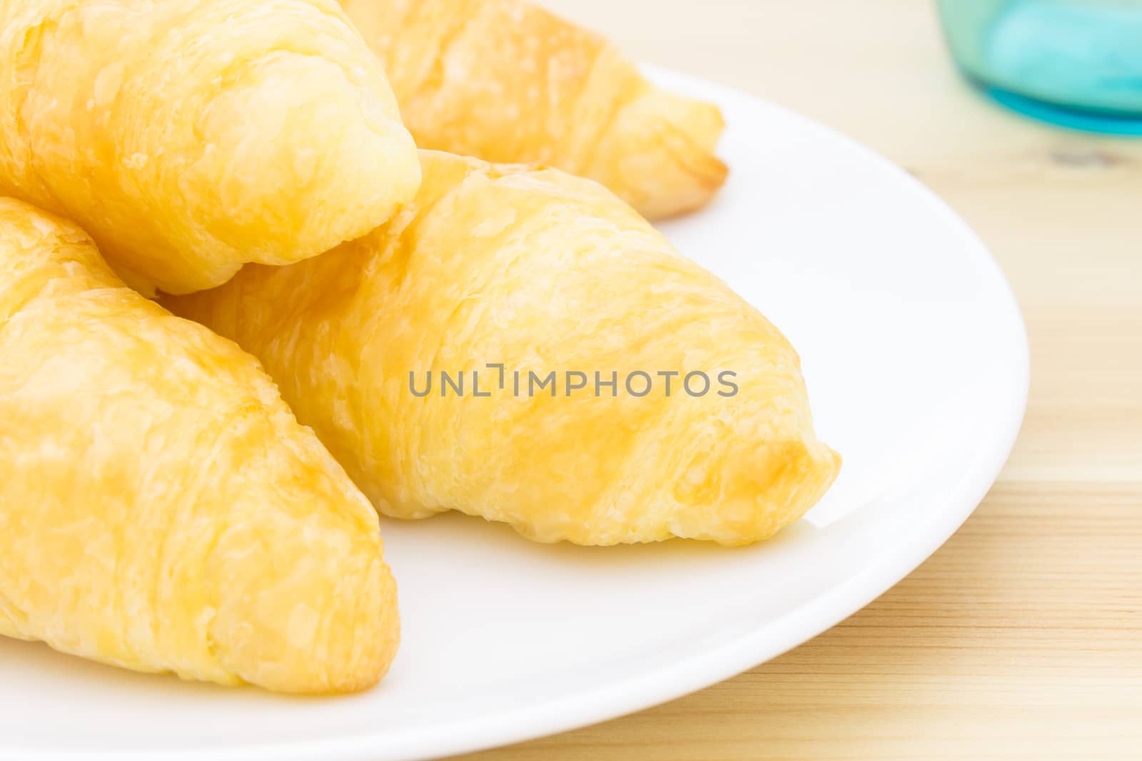 Croissant or bread or bakery on white dish on wood table and glass close up view