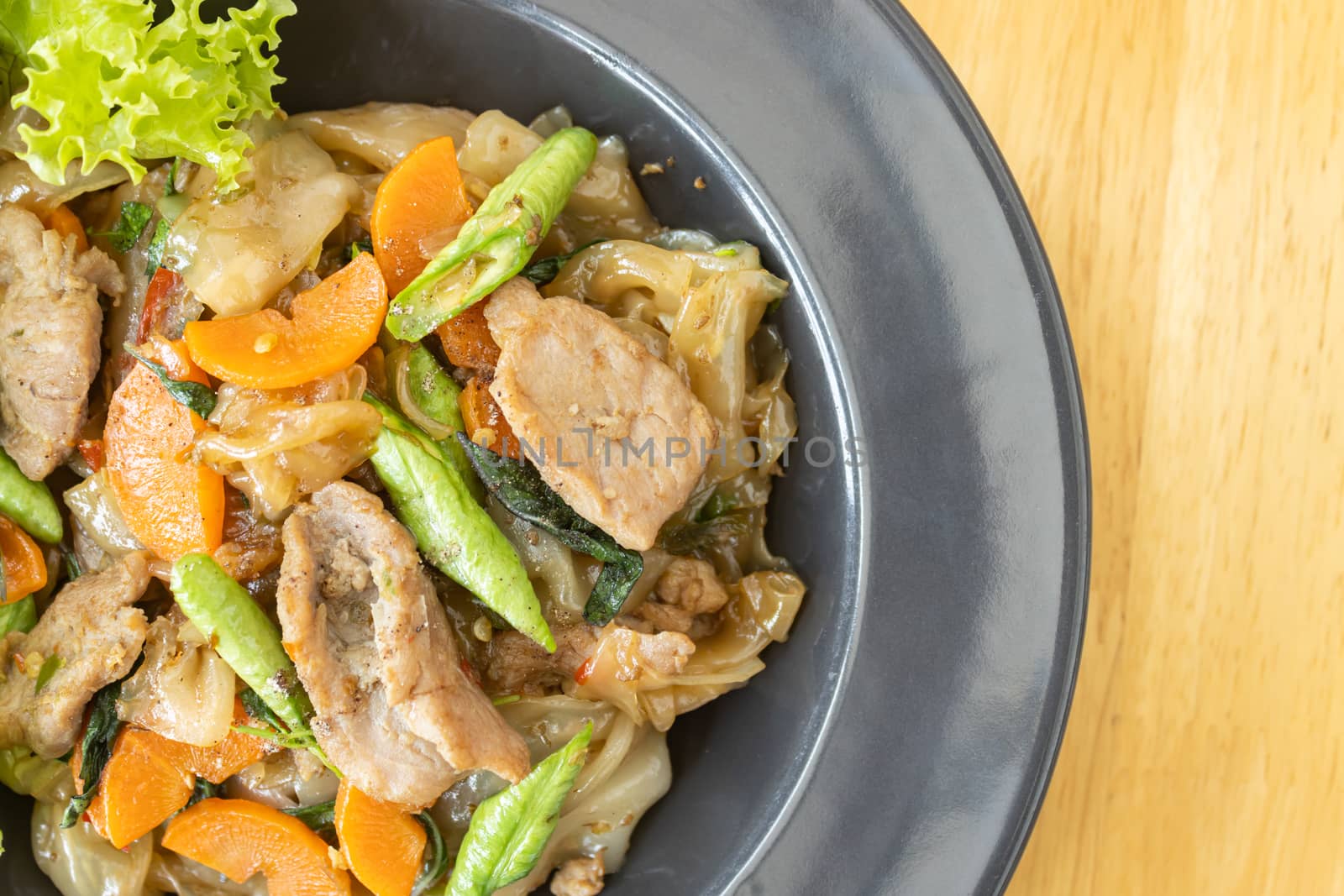 Stir Fried Noodle and Pork and Carrot and Yardlong Beans and Lettuce with Black Soy Sauce on Top View with Natural Light in Left Frame