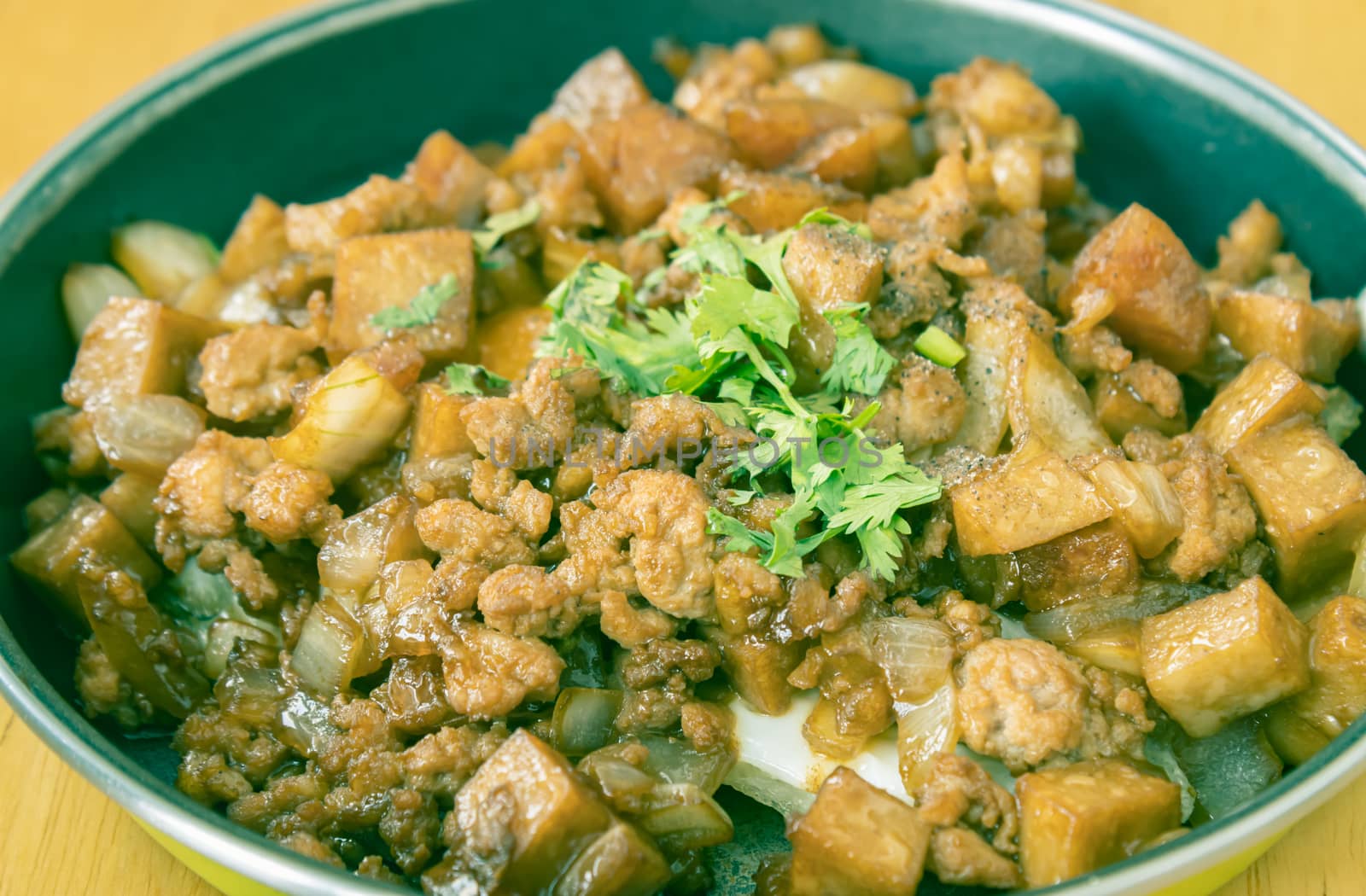 Stir Fried Pork with Onion and Garlic and Black Soy Sauce and Coriander Topping and Tofu in Pan on Wood Table with Natural Light in Zoom View in Vintage Tone