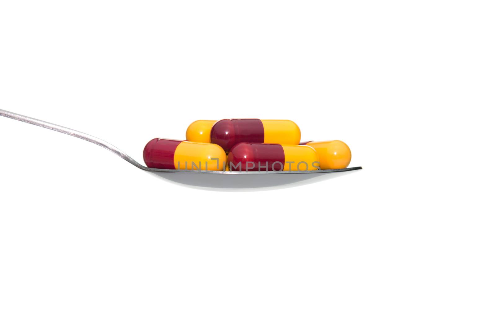 Red yellow drug or pill or vitamin on metal Spoon isolated on white background. Concept about health care or medical or science including food concept.