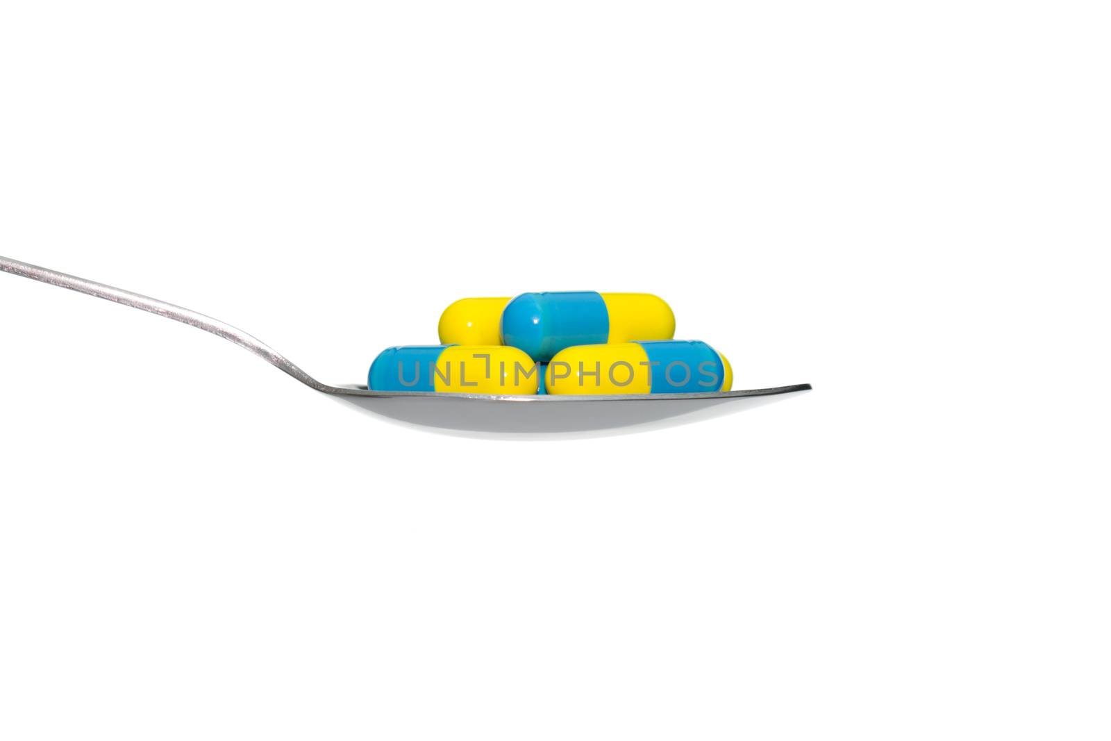 Blue Yellow drug or pill or vitamin on metal Spoon isolated on white background. Concept about health care or medical or science including food concept.