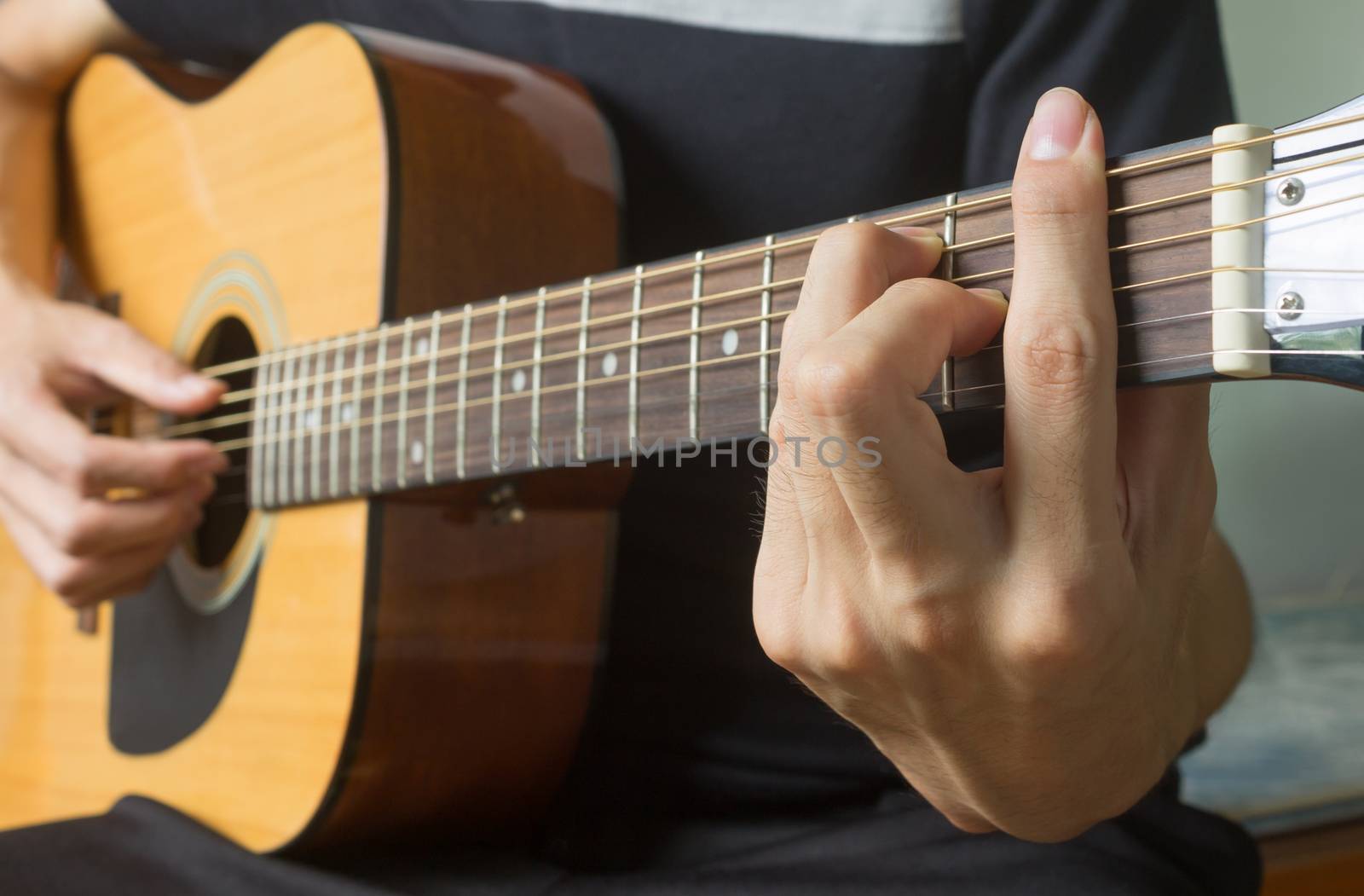 Guitar Player Hand or Musician Hand in F Major Chord on Acoustic Guitar String with soft natural light in side view