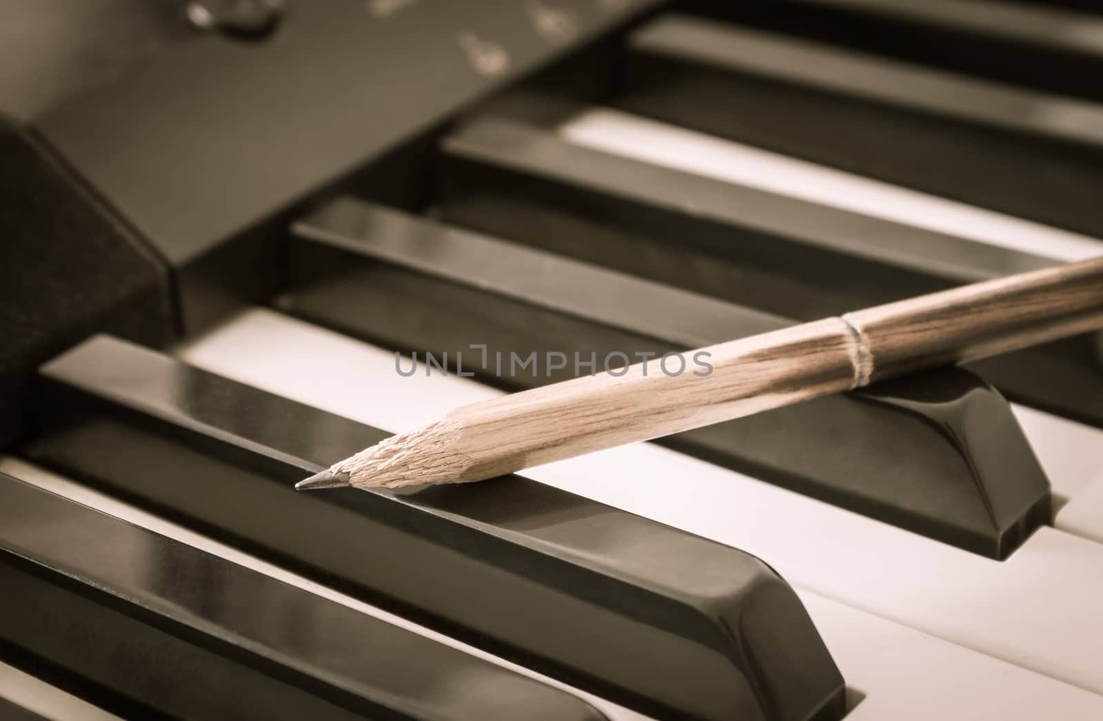 Old Pencil on Black Keys of Electric Piano in Crosswise View. Concept about Piano Playing or Piano Learning