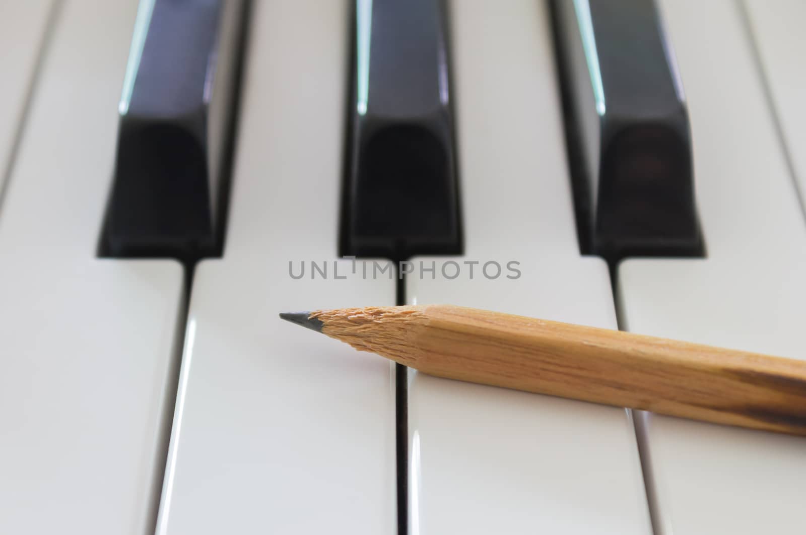 Old Pencil on White Keys of Electric Piano in Crosswise View. Concept about Piano Playing or Piano Learning