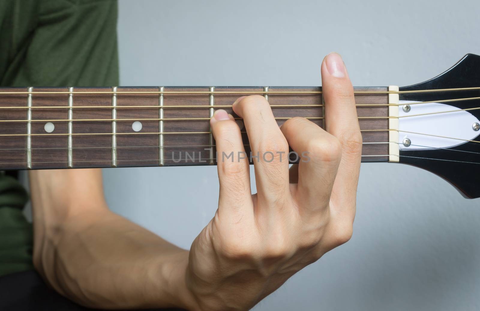 Guitar Player Hand or Musician Hand in F Major Chord on Acoustic Guitar String with soft natural light in close up view