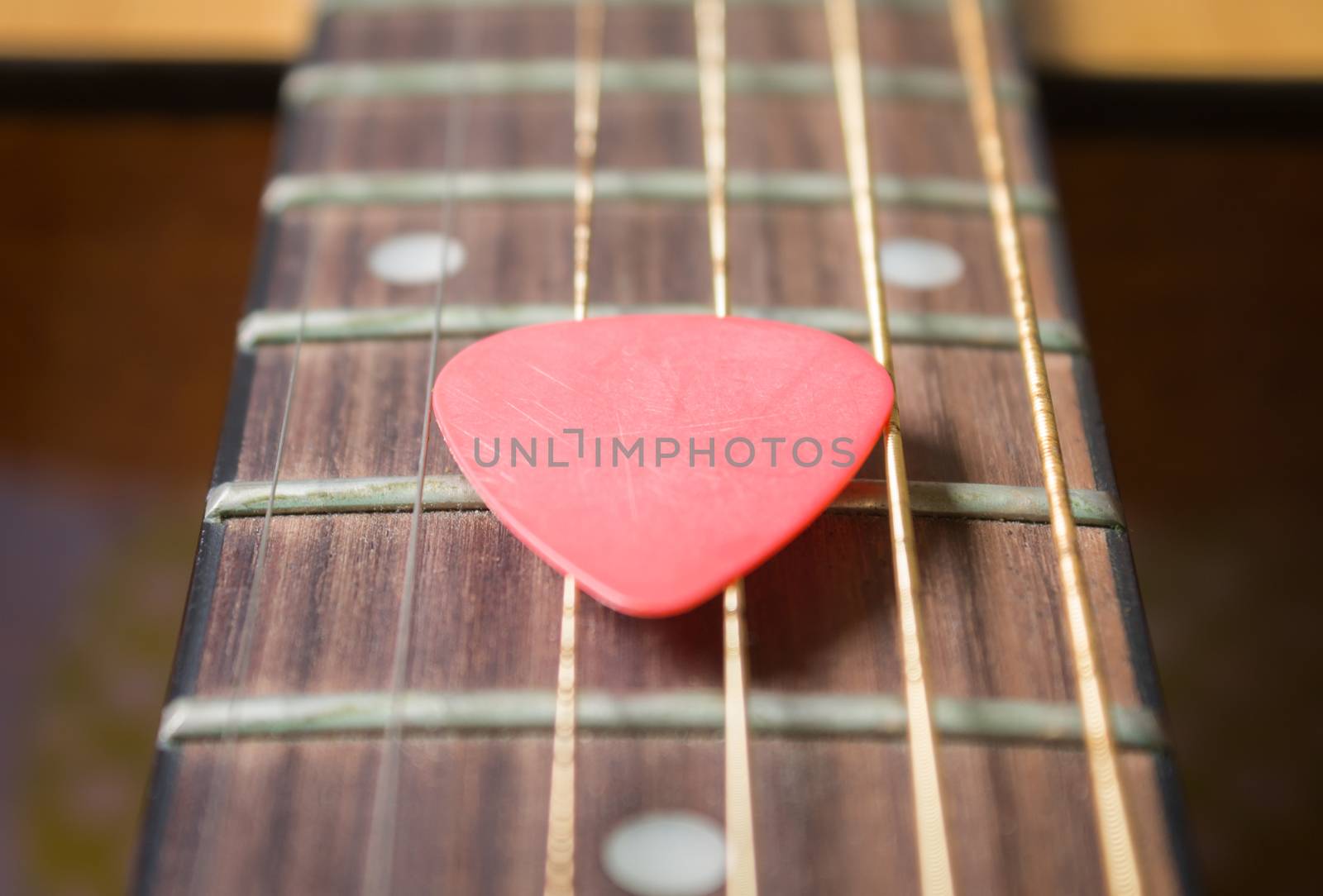 Red Pick on Acoustic Guitar String and Fingerboard or Fretboard in Zoom view