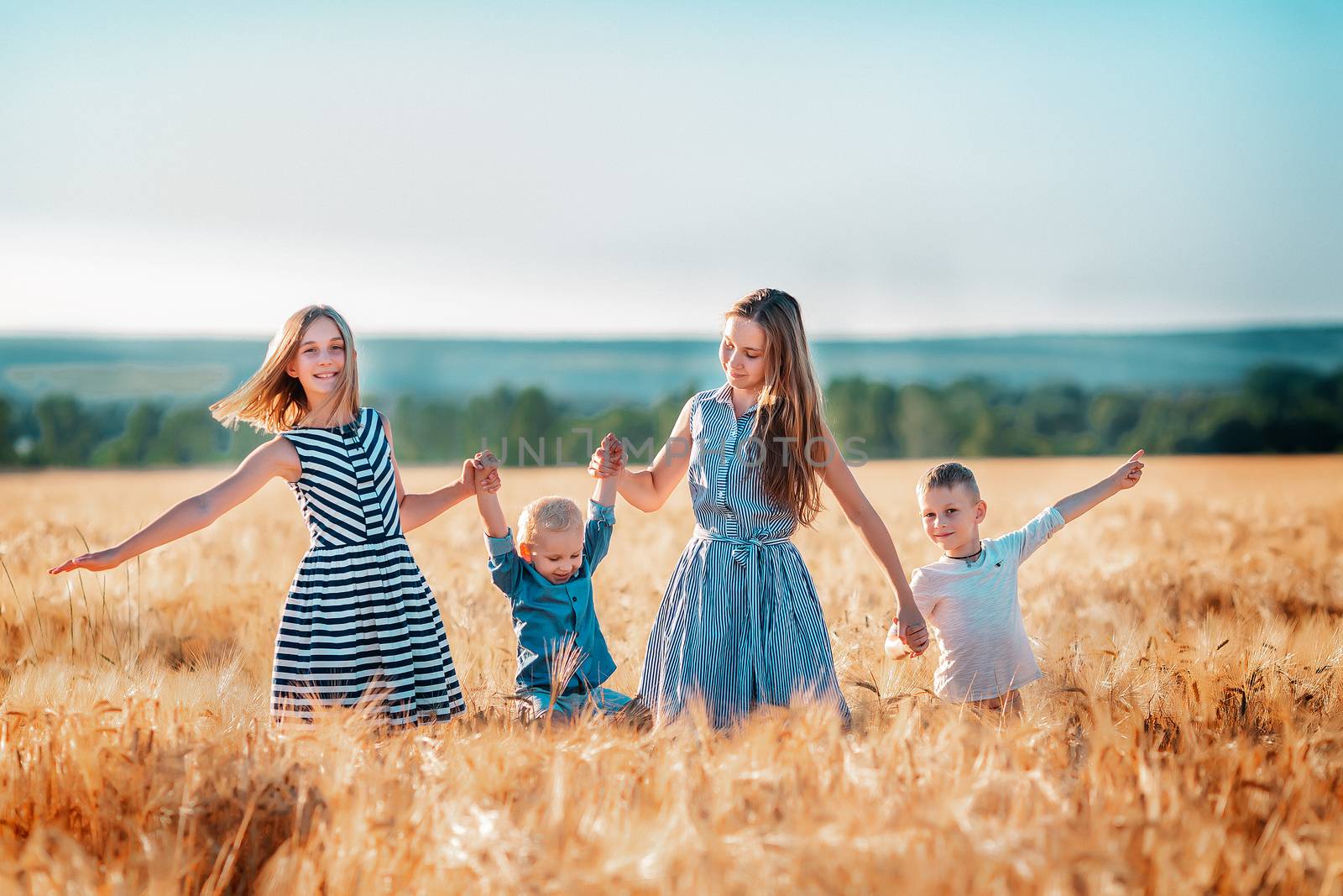 Happy kids having fun in golden wheat field at the sunset
