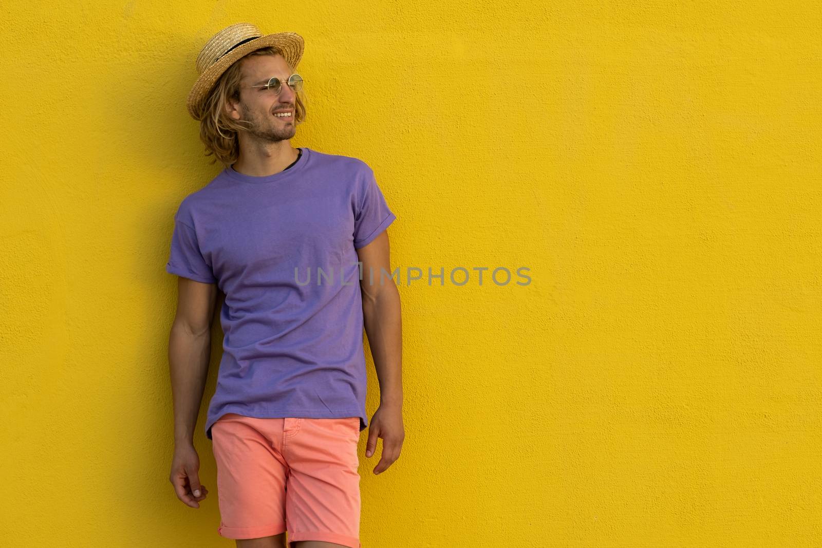 Young blond man with summer clothes, hat and sunglasses enjoying the summer