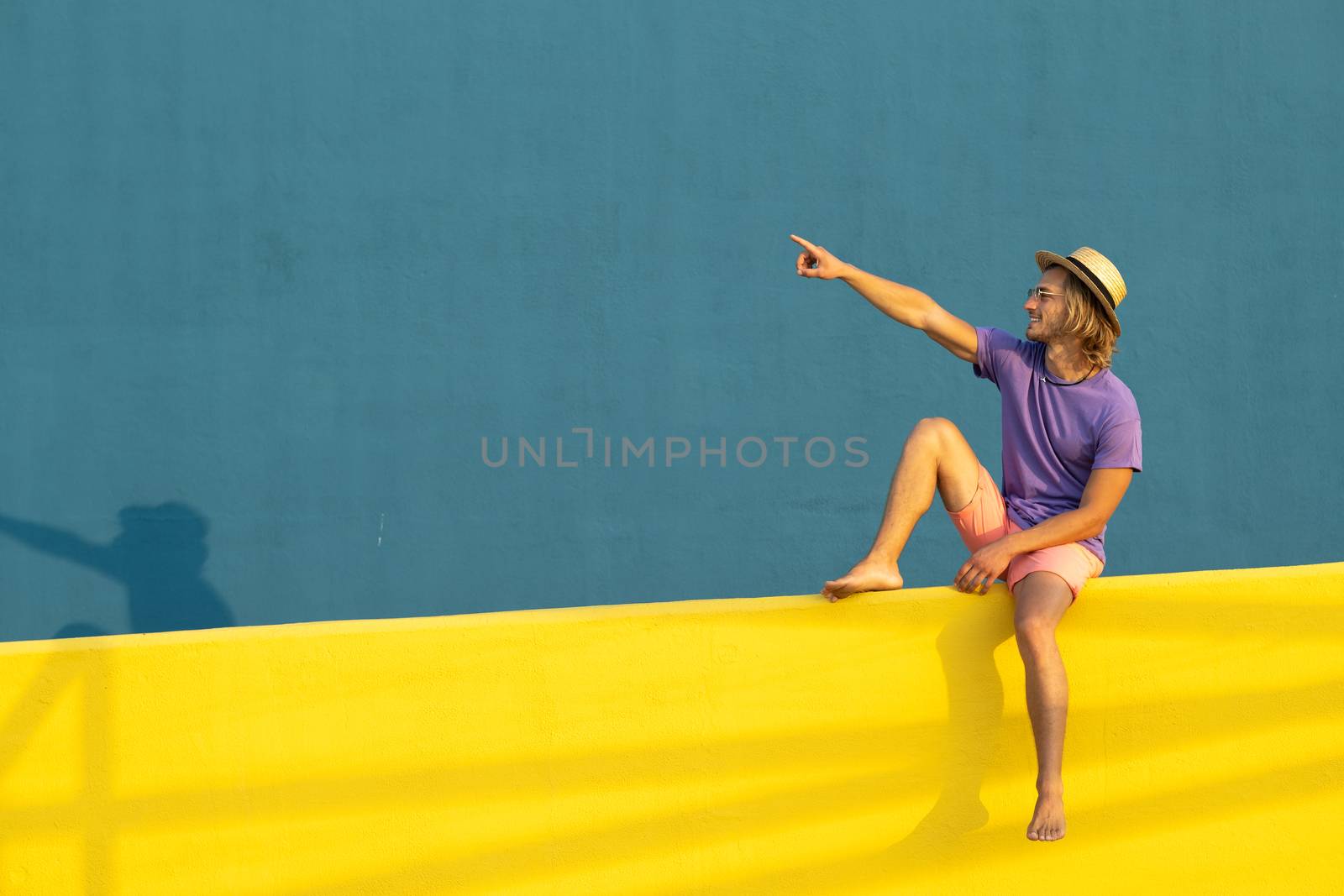 Young blond man with summer clothes, hat and sunglasses enjoying the summer