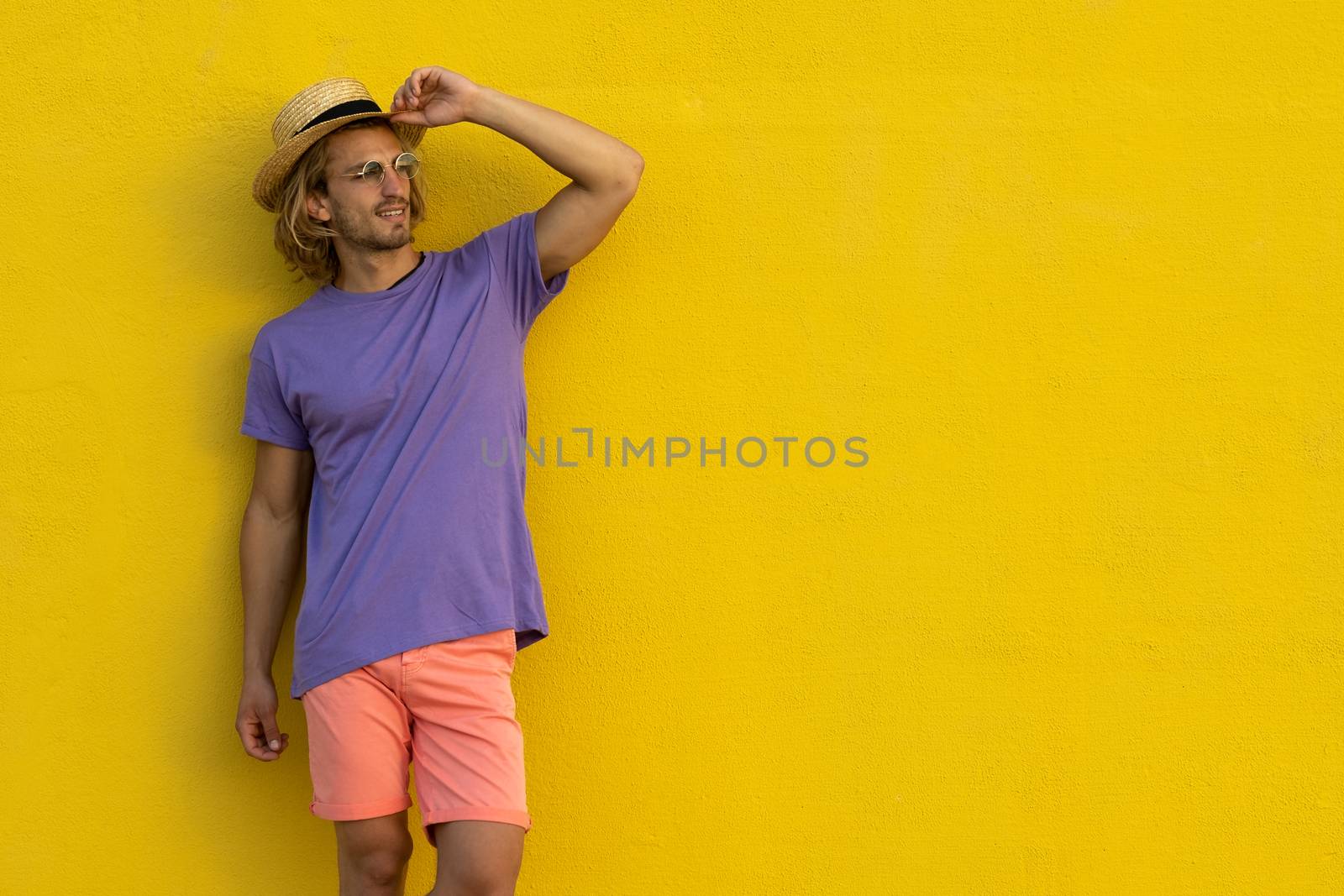 Young blond man with summer clothes, hat and sunglasses enjoying the summer