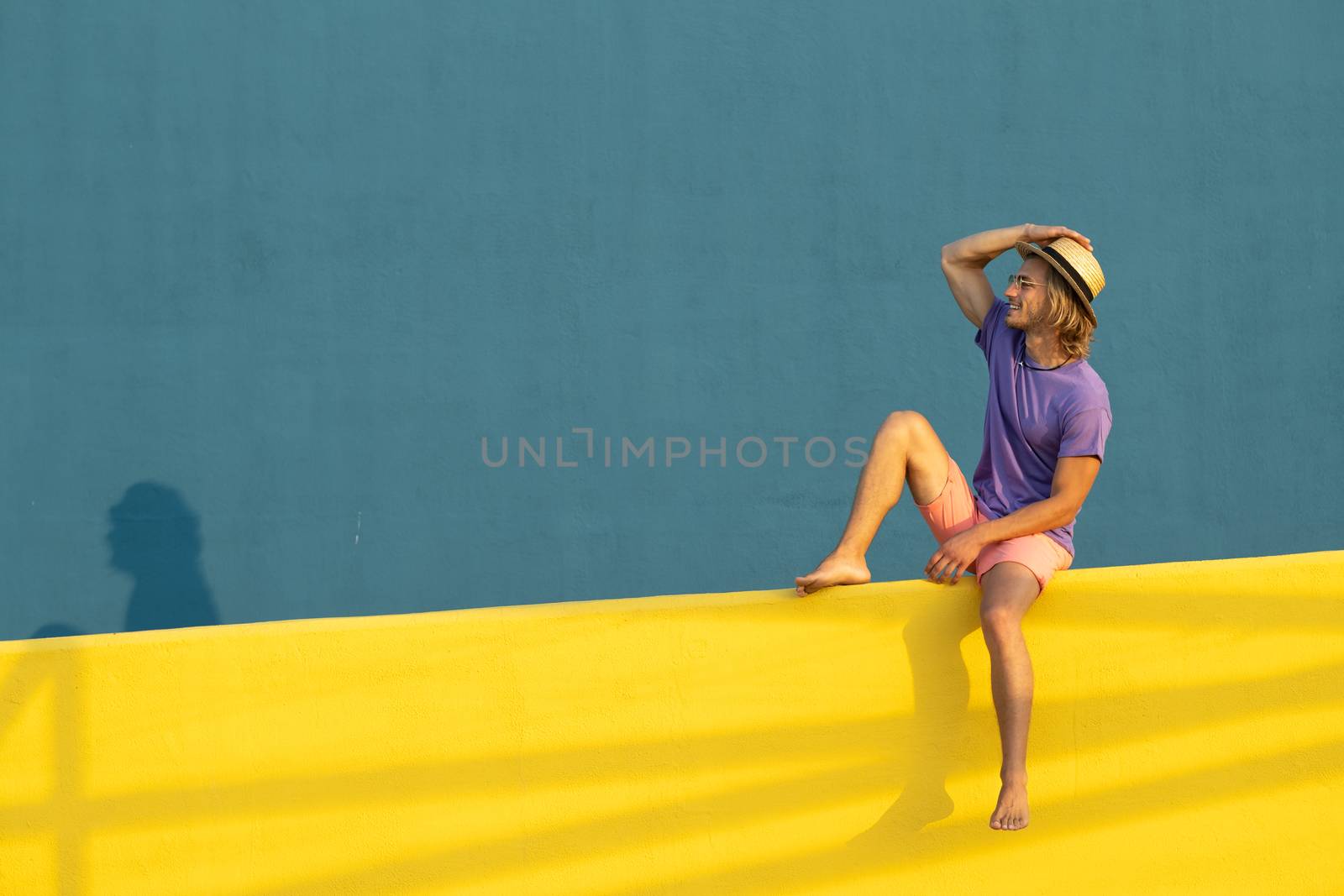 Young blond man with summer clothes, hat and sunglasses enjoying the summer