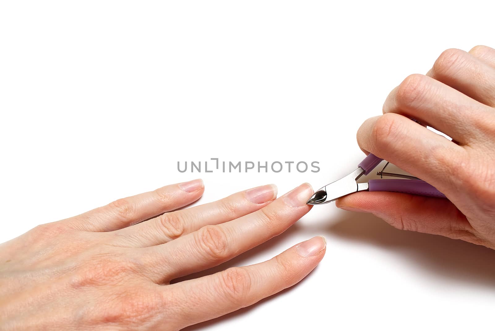 Woman's hand removing nail cuticle on light white table. Care about dry, overgrown cuticle. Closeup