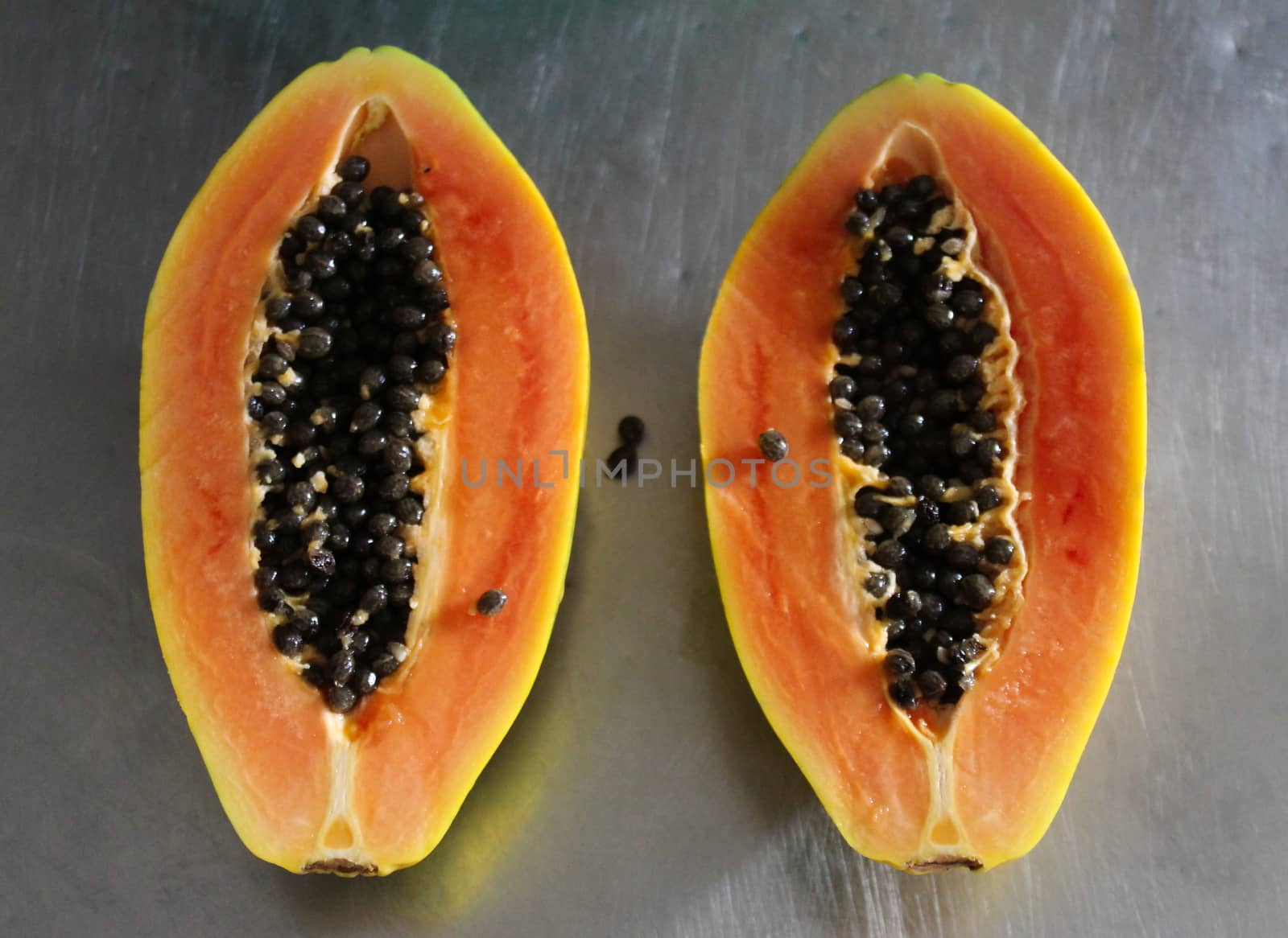 Two halves of papaya fruit on the kitchen table.