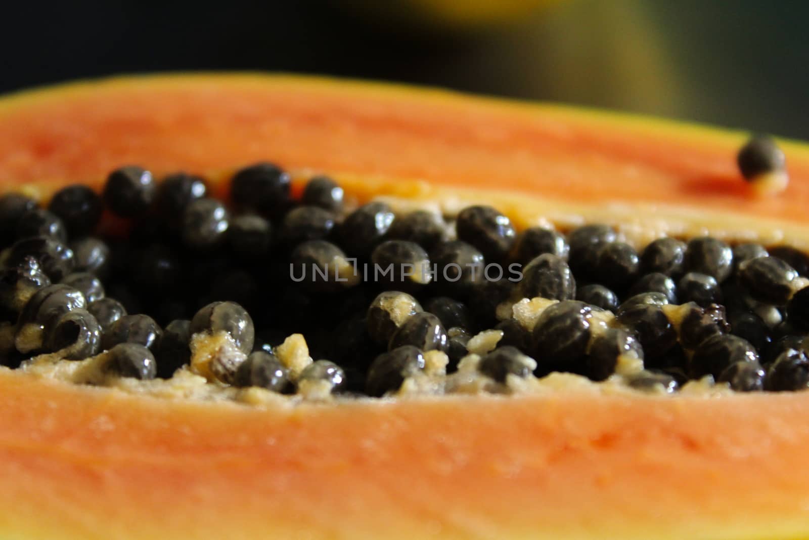 Half a papaya fruit, close up of black papaya seed.