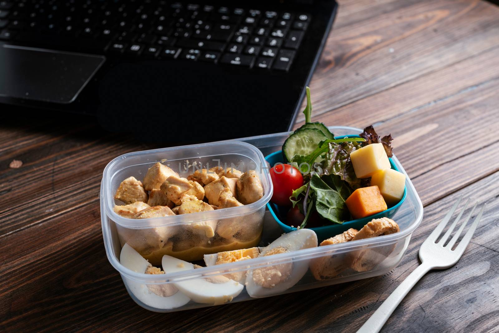Healthy food in lunch box, on working table with laptop .eating at workplace. Home food for office concept 