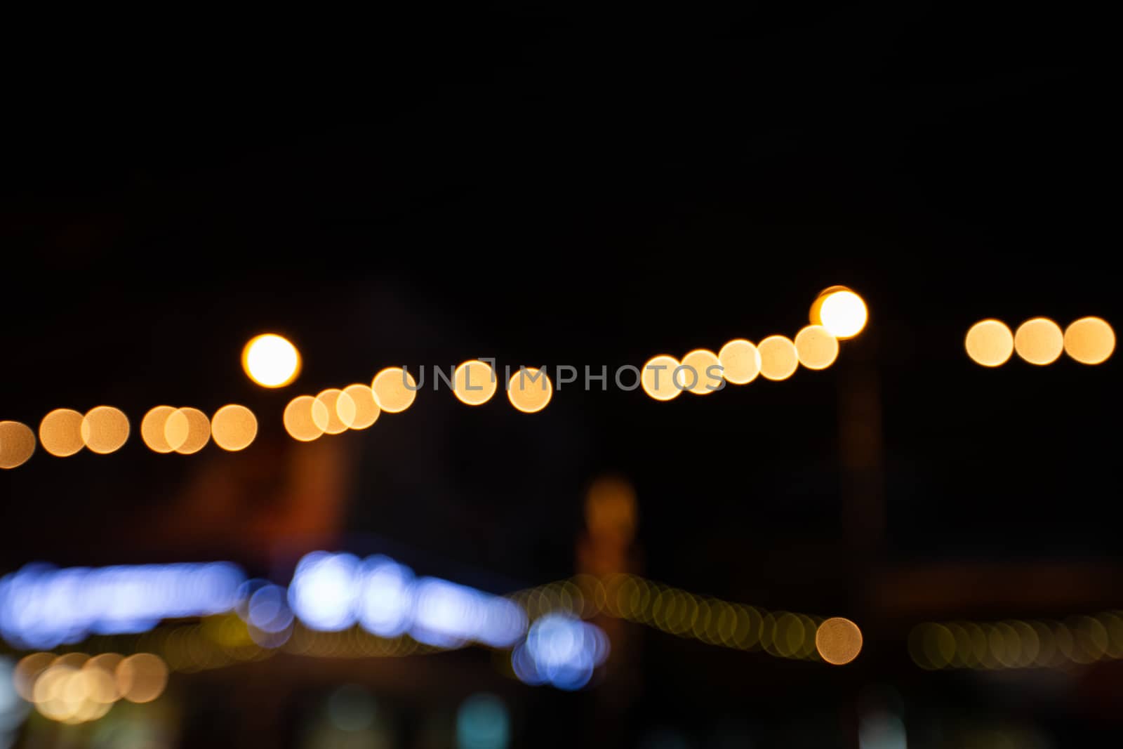 Abstract blurred traffic city of Night market on street light bokeh background. Bangkok, Thailand Cityscape at twilight time concept: focus in Motion blur,  Modern business building estate nightlife.