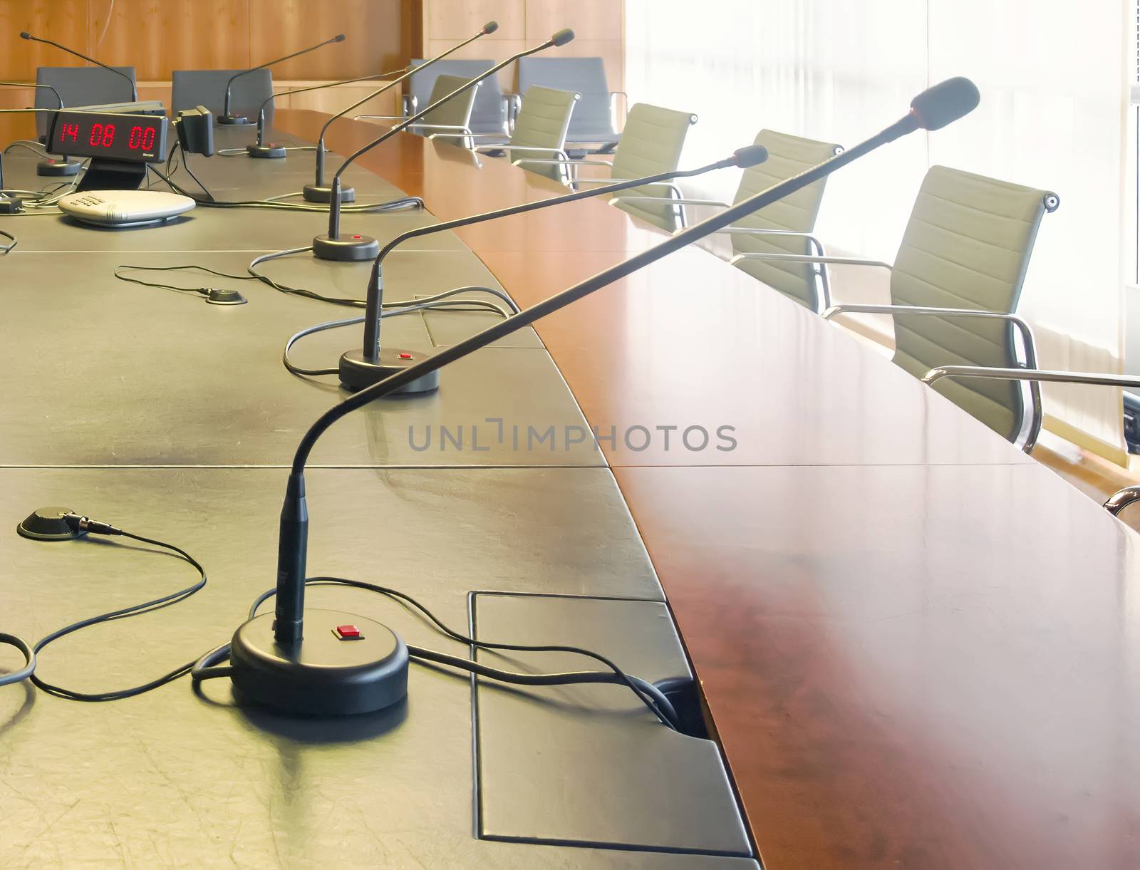 Microphone on a wooden table and empty chairs in a boardroom. by rarrarorro