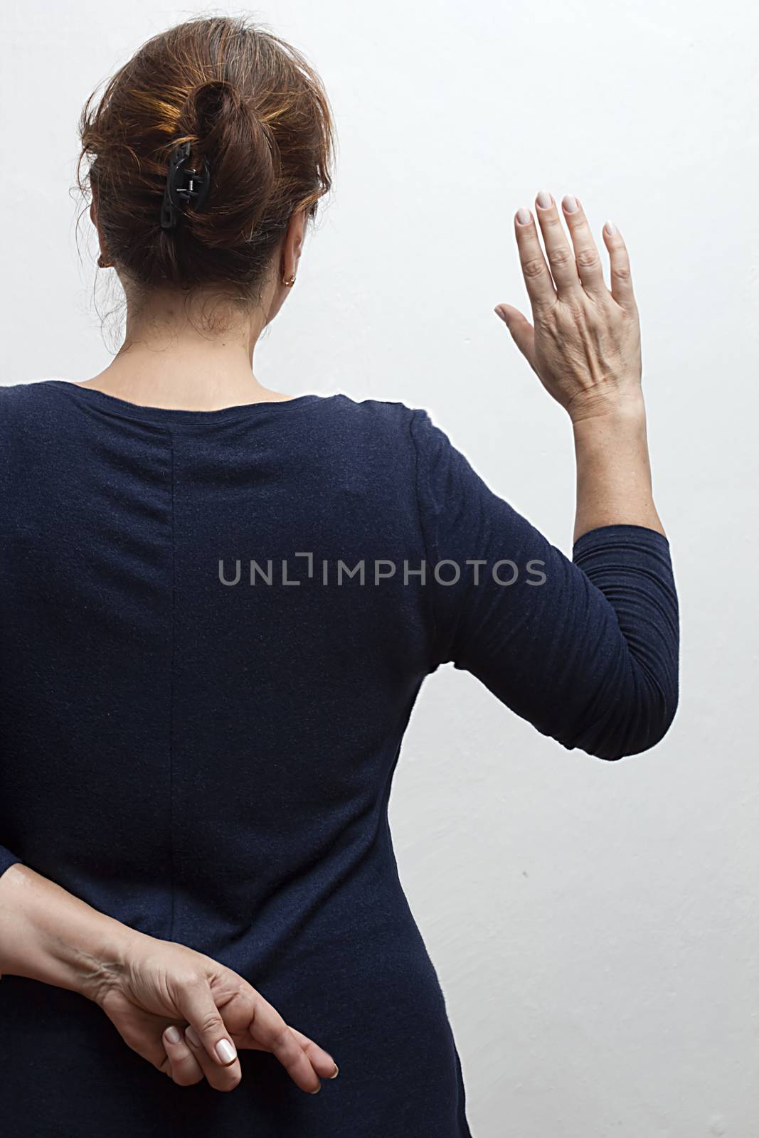 Woman takes an oath and holds her crossed fingers behind her back.