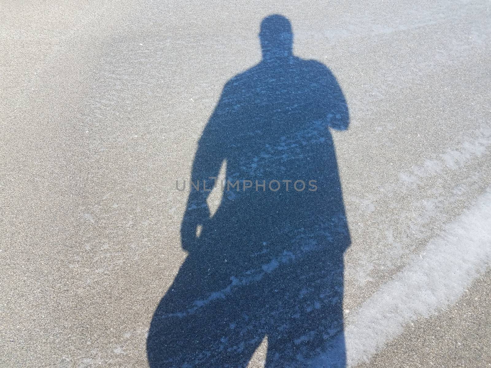 shadow of man on wet sand at beach with water by stockphotofan1