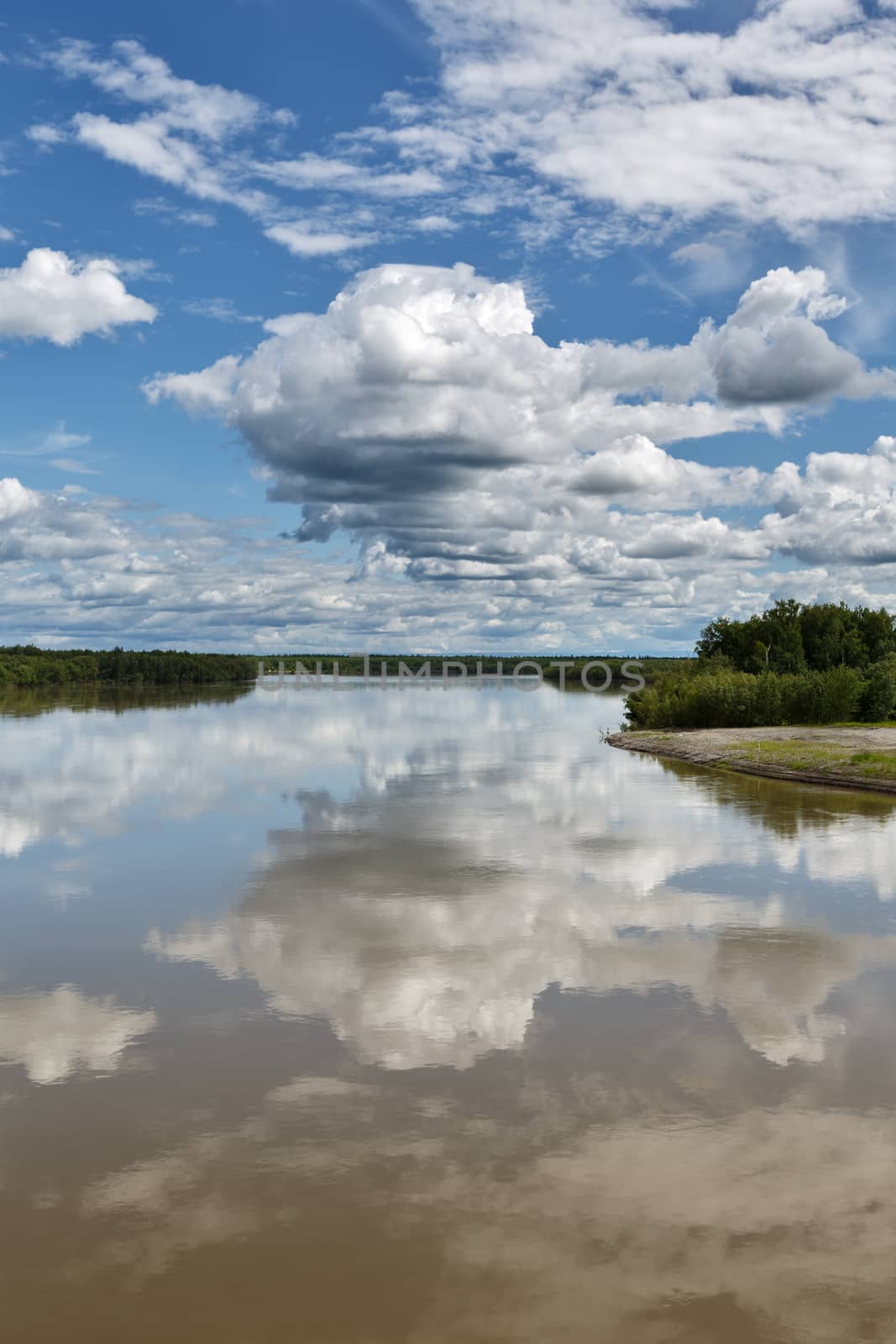 Beautiful summer landscape: view on Kamchatka River, beautiful clouds and reflection in water. Russia, Far East, Kamchatka Peninsula.