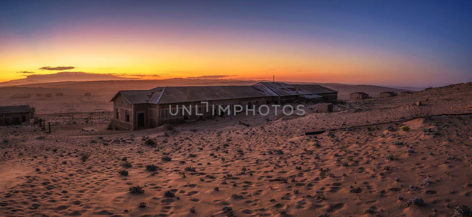 Colorful sunrise above the abandoned houses of Kolmanskop ghost town located in southern Namibia near the town of Luderitz.