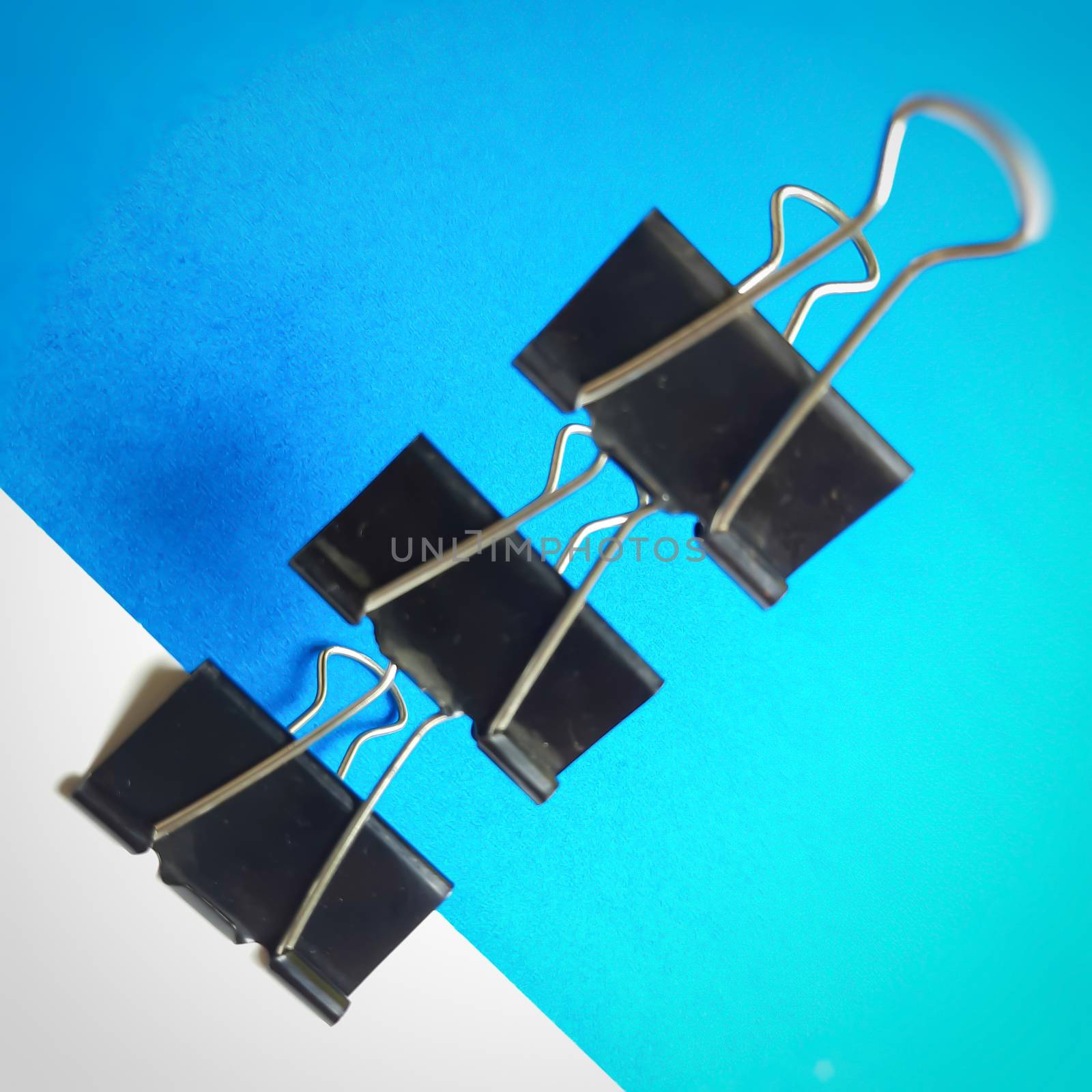 Three Black paper clips or chart clips arranged diagonally in white and blue background