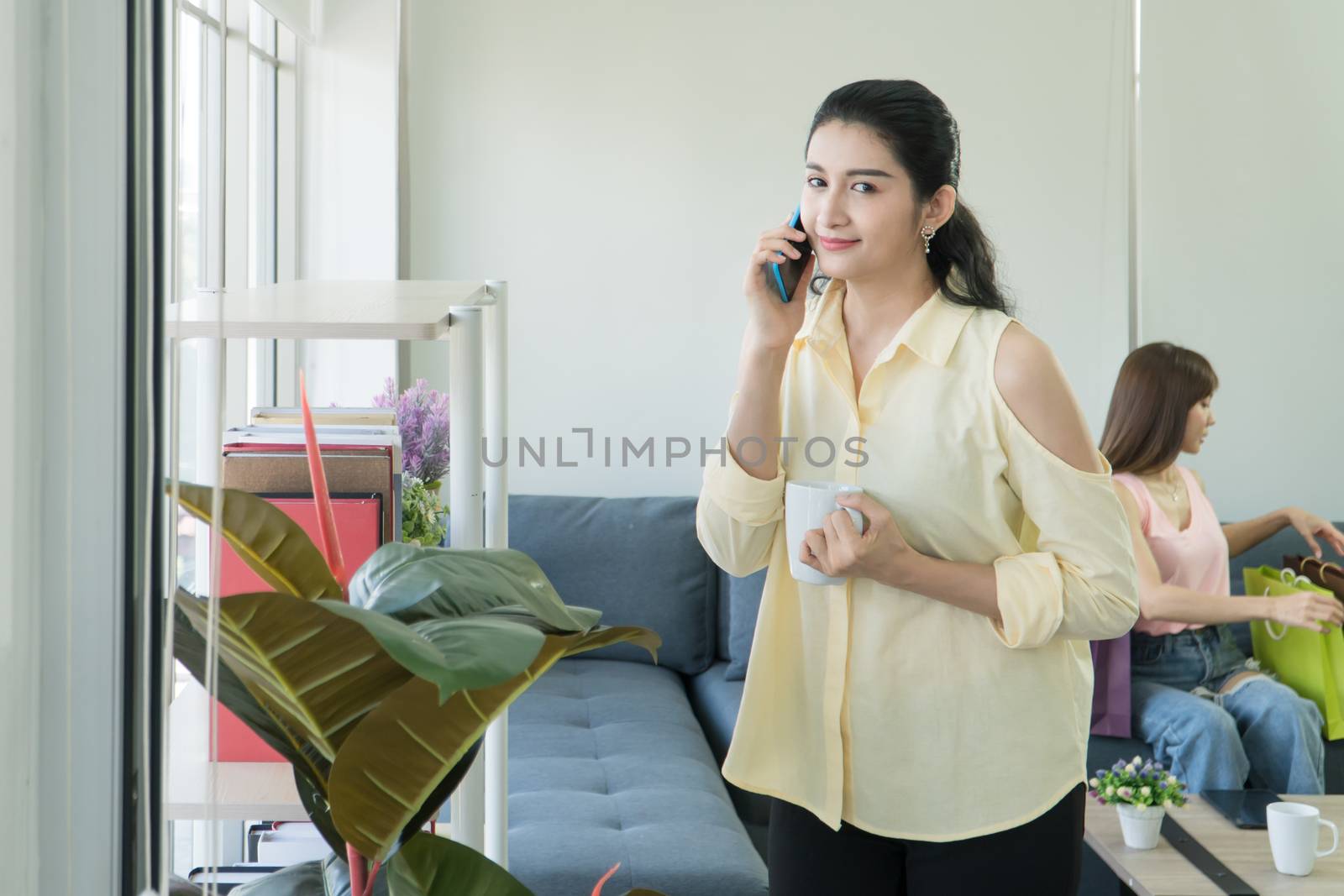 Portrait of an attractive, mature Asian woman talking on the phone and smiling happily at home on the fresh morning air and copy space.