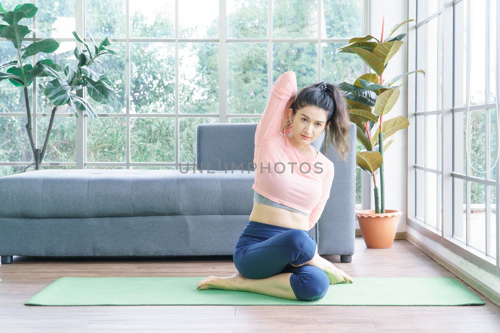 Attractive middle-aged women in Asia practice yoga, sit meditation For a balanced life at home. Sporty wears Sportswear to stretch the body with asana administration positions.