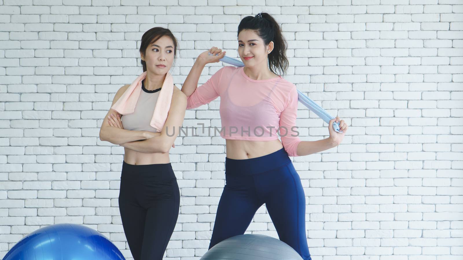 A group of young Asian women wearing sportswear is talking about sports in the gym after exercising by doing stretching with yoga postures.