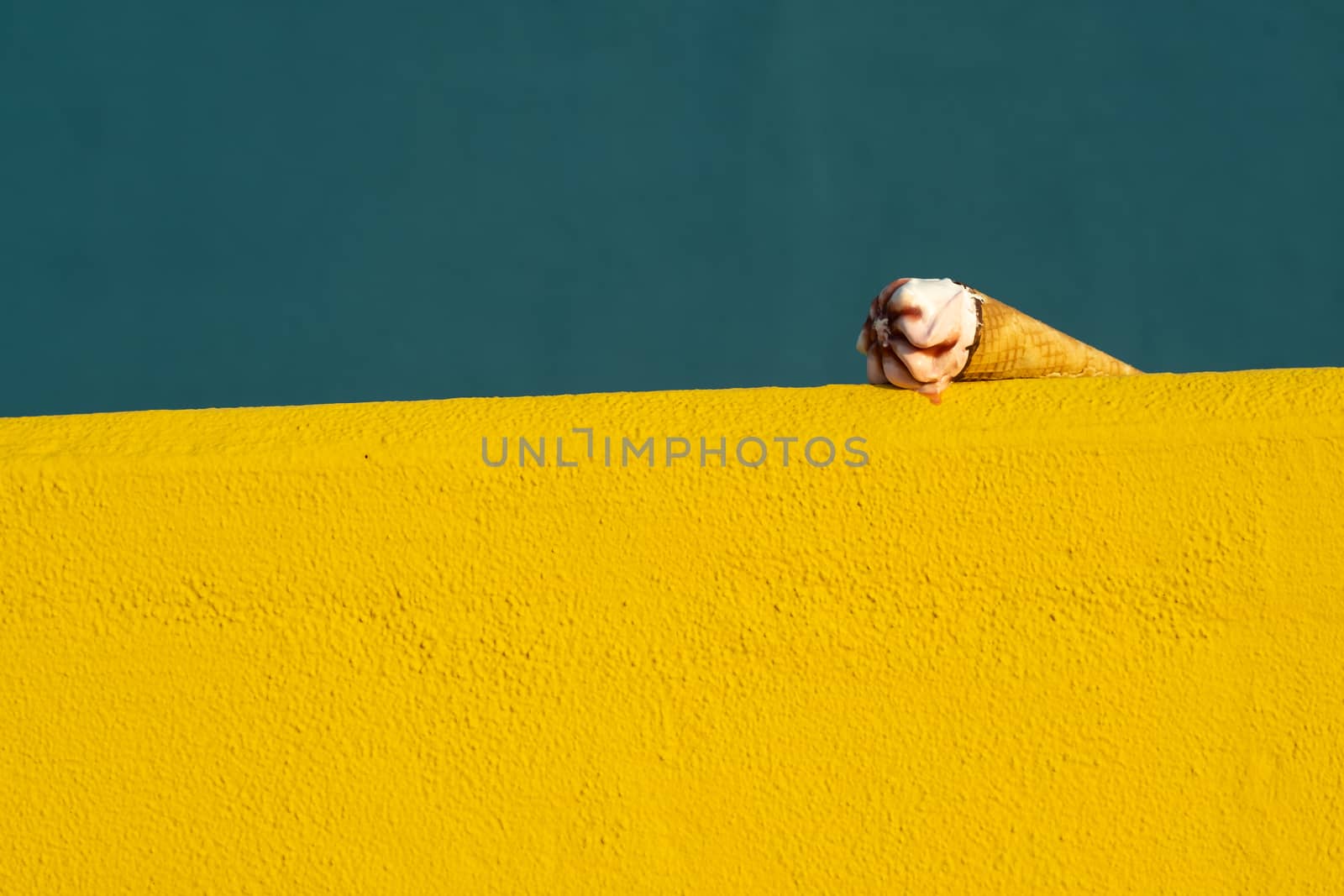 Ice cream with a cone melting in summer with the heat of the sun on a yellow and blue background. Vacation concept