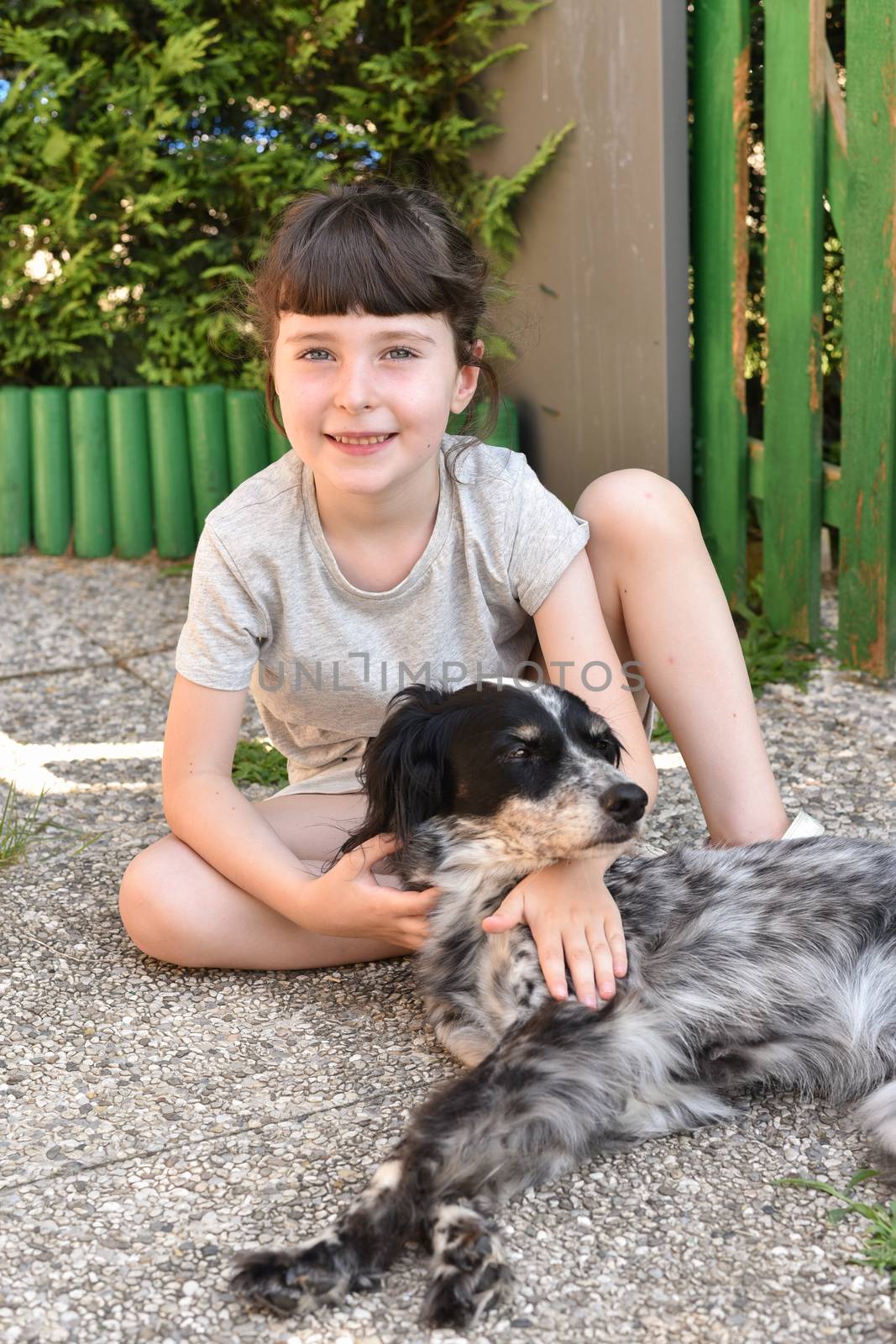 A little girl sits outdoors next to her dog, portrait set outdoors with a pet