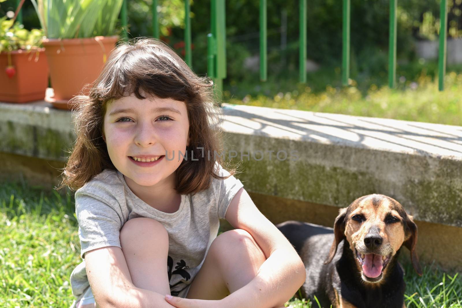 A little girl sits outdoors next to her dog, portrait set outdoors with a pet