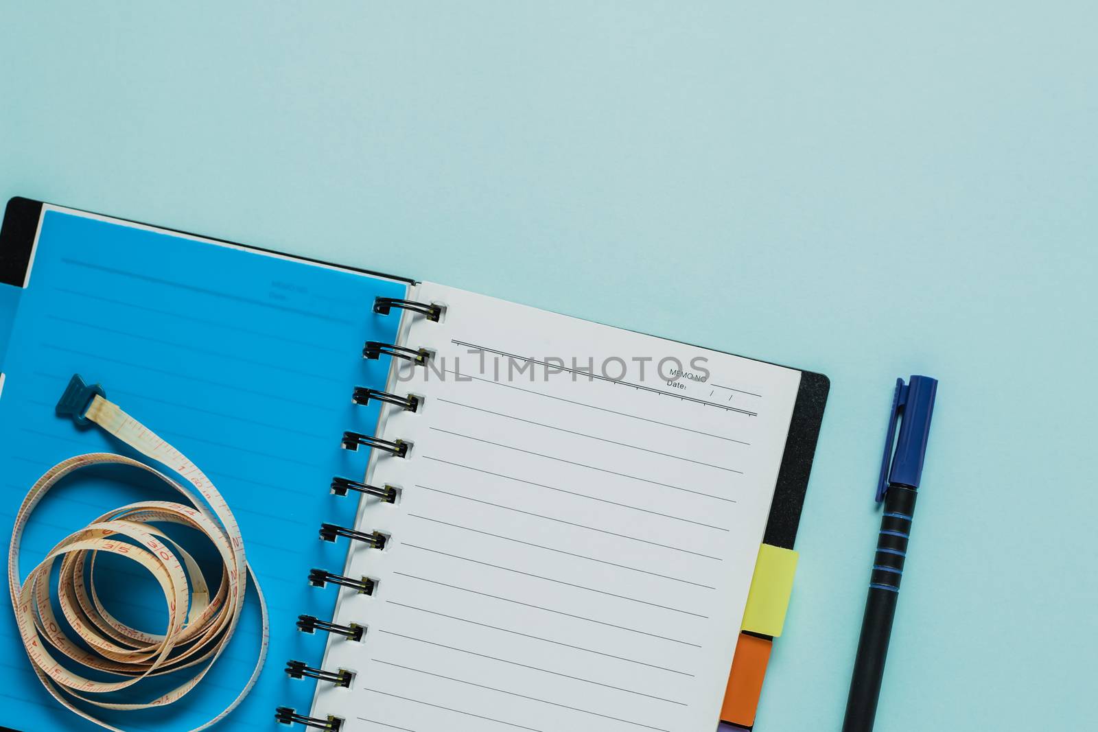 Notebooks with measure tape on blue background for healthy diet taking notes concept