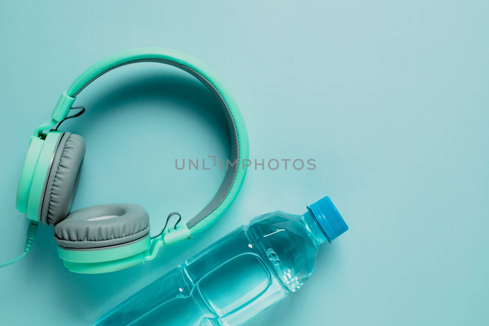 Fresh drinking water with headphones on blue background for healthcare and relaxation concept