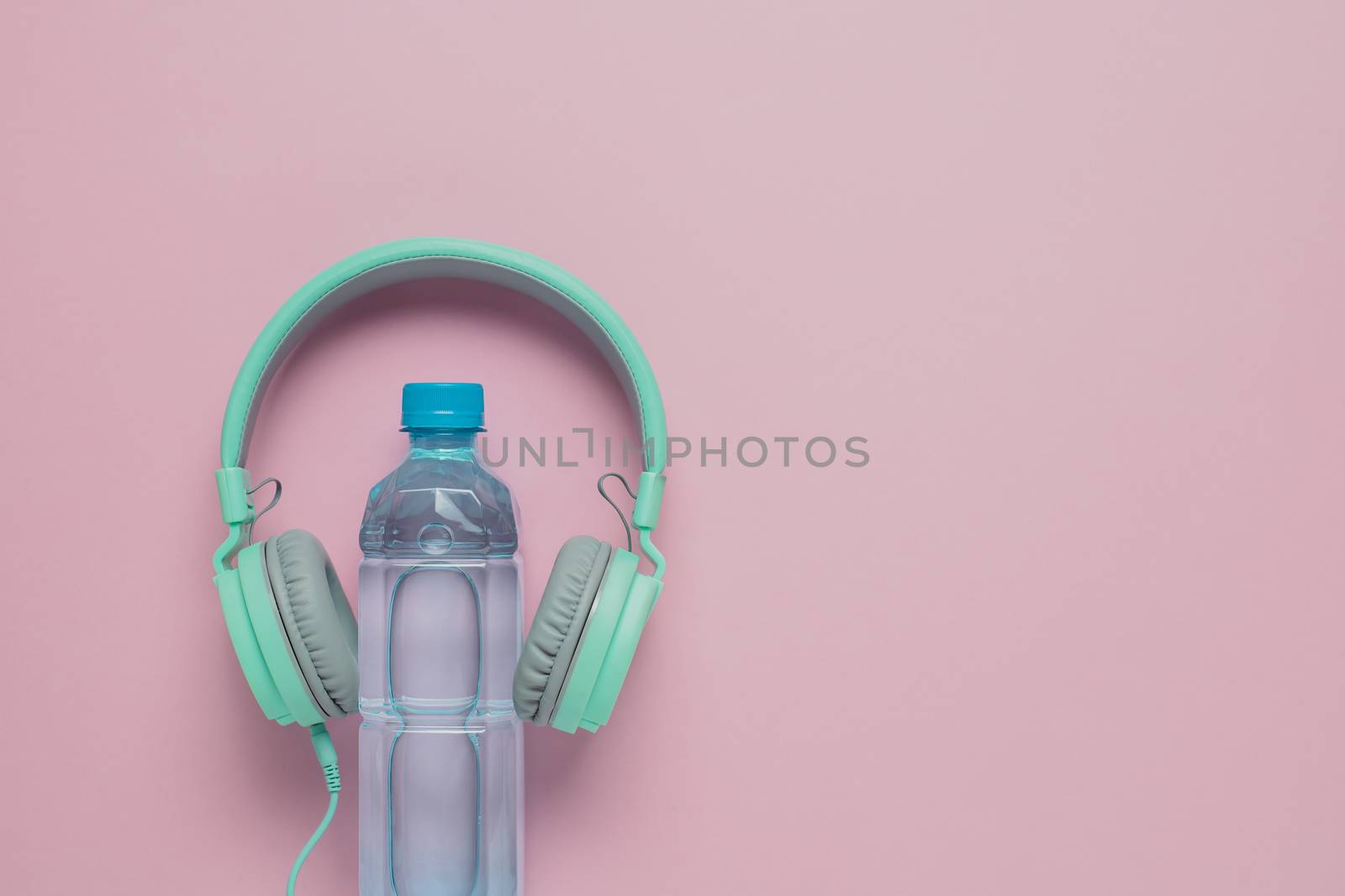 Fresh drinking water with headphones on pink background for healthcare and relaxation concept