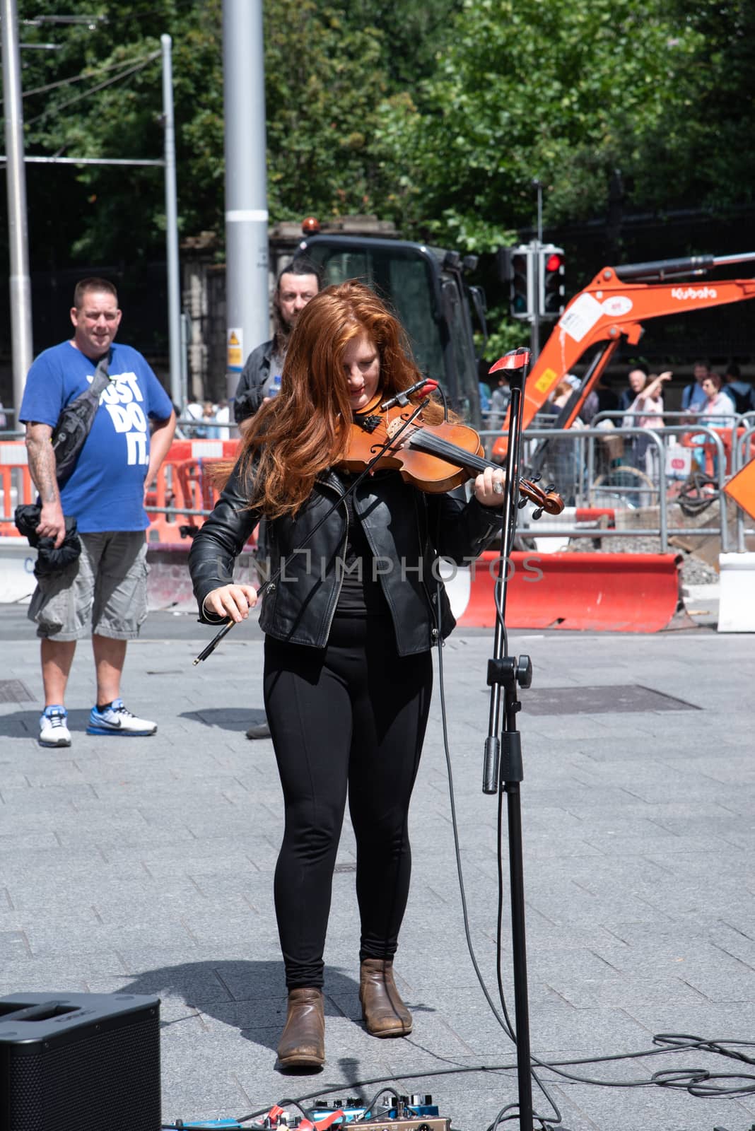 Dublin, Ireland--July 16, 2018. A musician playing the violin on the street with pedestrians in the background.