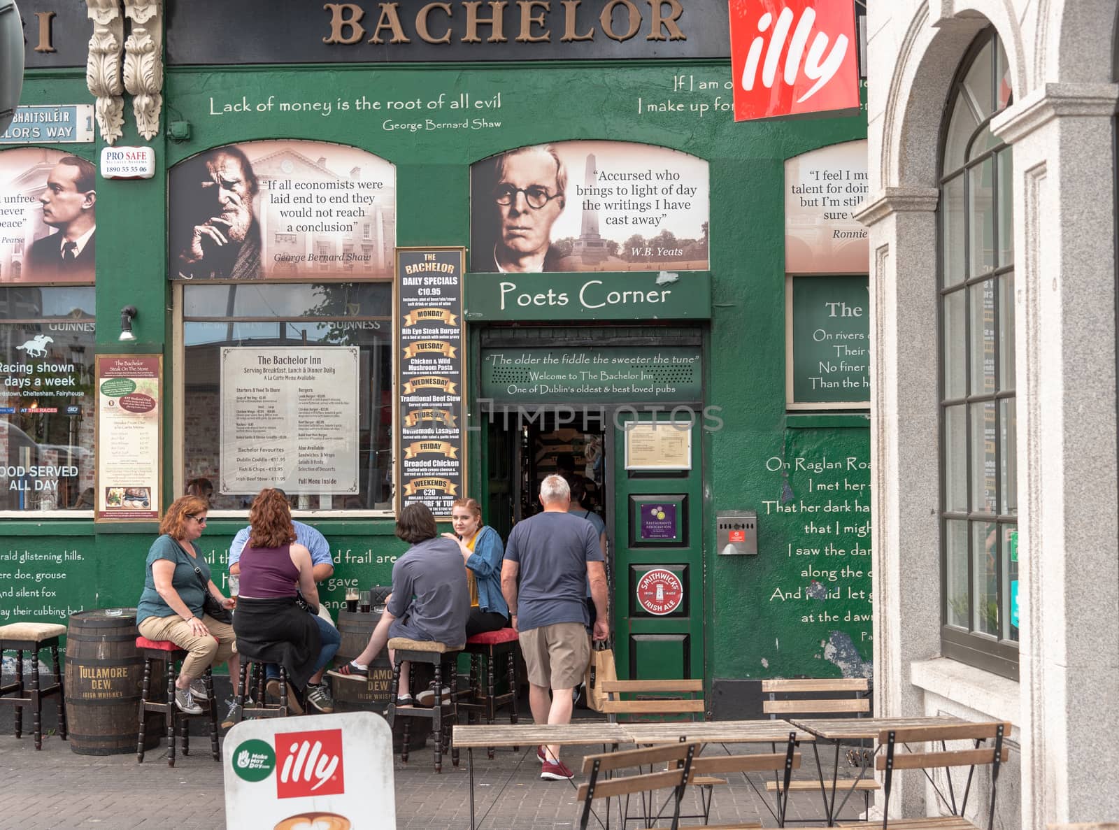 Dublin, Ireland--July 9, 2018. People sit down and enjoy a pint outside a pub in Ireland. A man is entering the doorway.