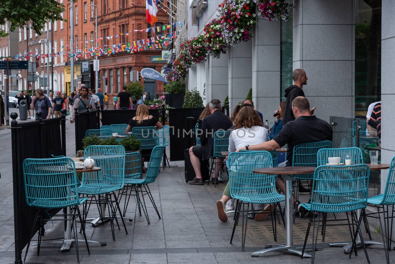 Dublin, Ireland -- July 9, 2018. People sitting at an outdoor cafe in Dublin, Ireland having coffee while nearby pedestrians walk past.