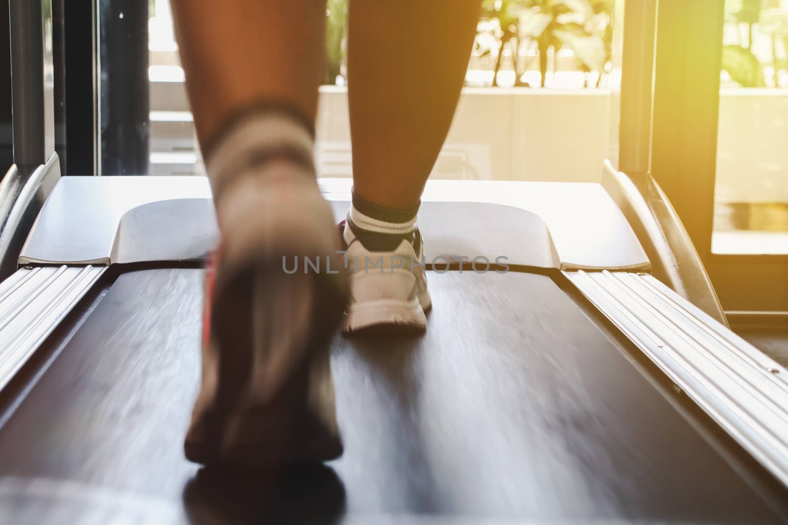 Close up shoes woman's running on treadmill. Woman with muscular legs in gym by anotestocker