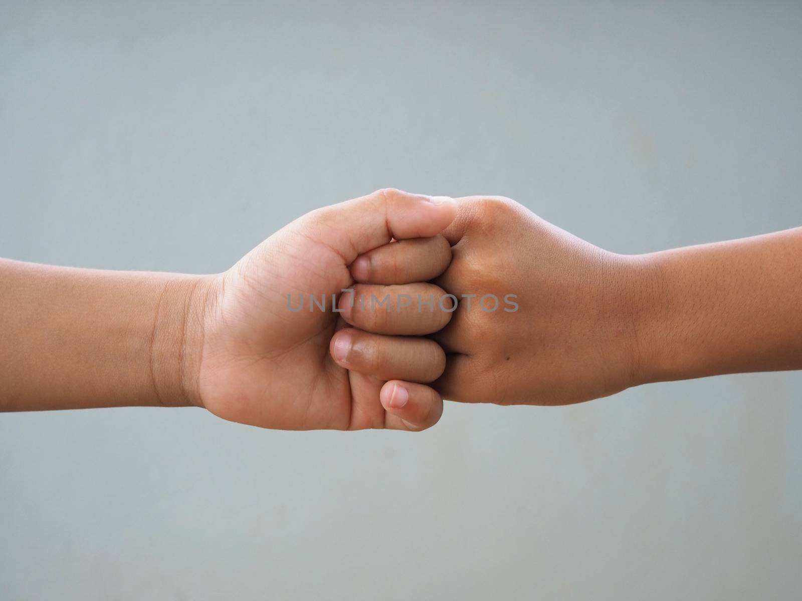 Boy fist bumping On a gray background.
It is a new greeting during the Covid virus epidemic prevention. clipping path.
new normal concept.