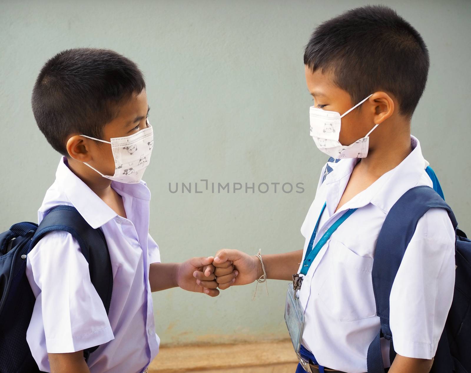 Students wearing masks to protect against viruses and  fist bump by Unimages2527